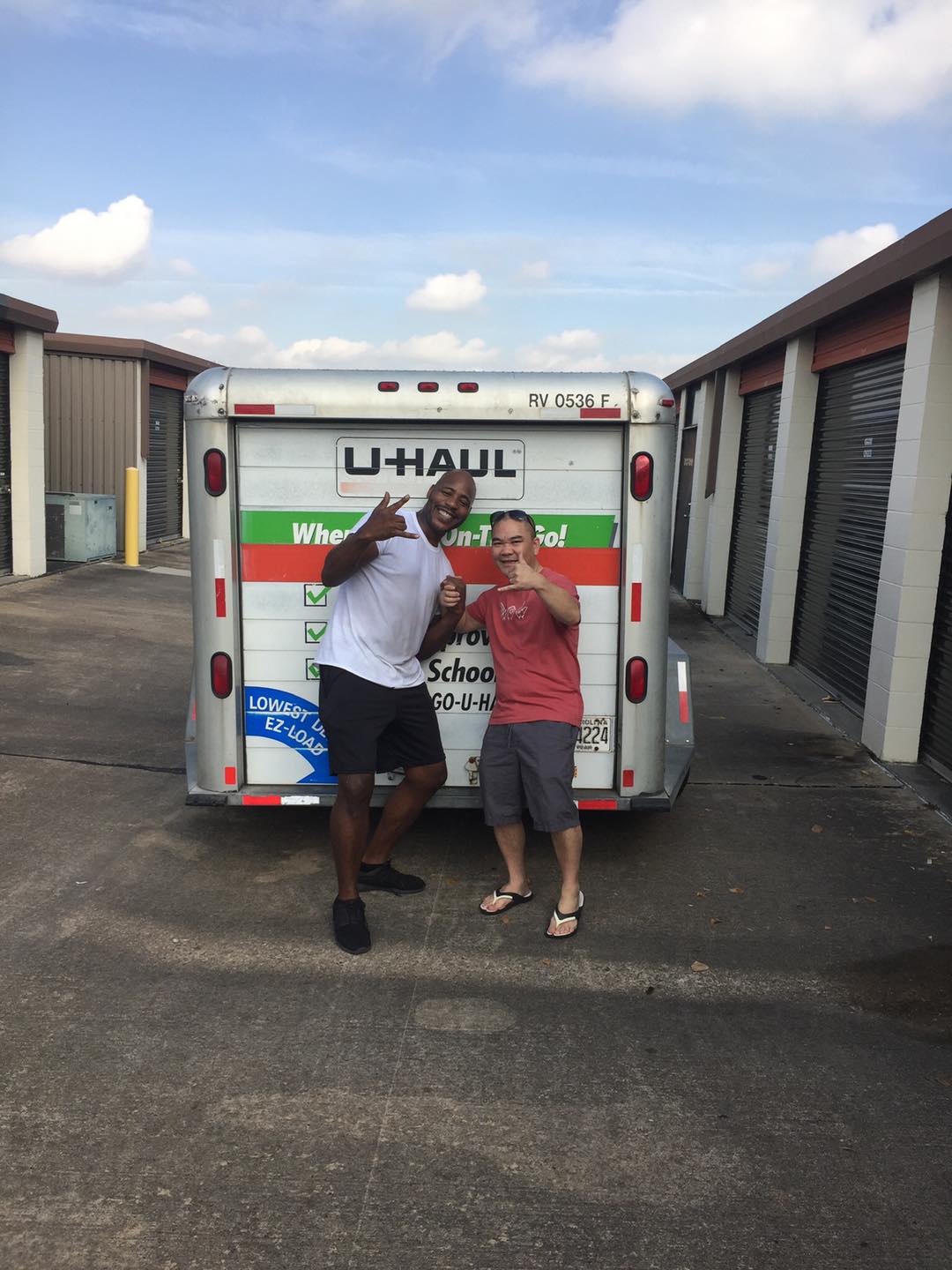 Photo of Horace Hodges of Hodges Family Movers posing with smiling customer behind U-haul trailer in the middle of roadway separating storage units at local storage facility in Houston area