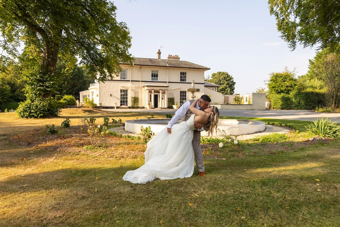 Lauren and Ethan embracing in the gardens at Highfield Hall near Chester during golden hour