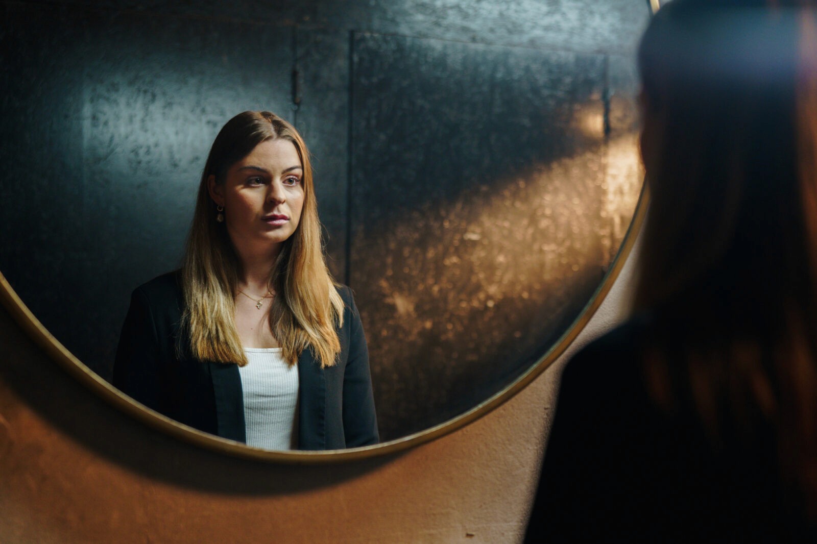 The image captures a young woman looking into the mirror