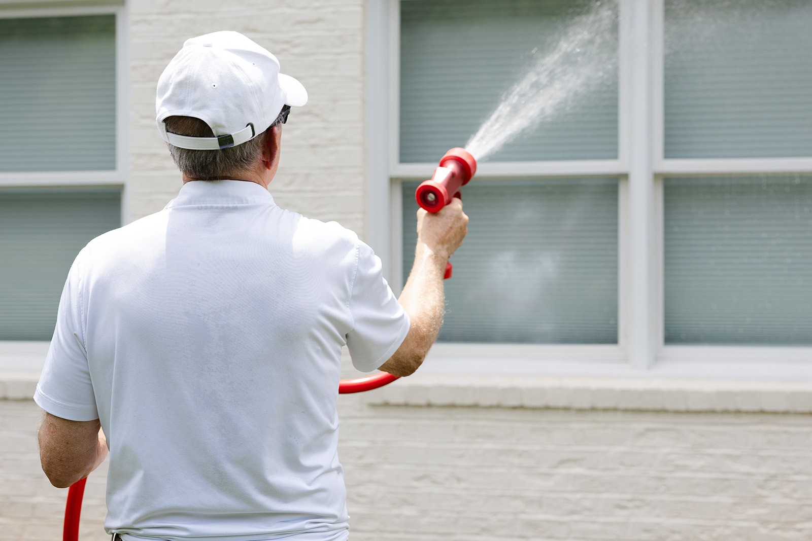 a worker washing the siding of a house
