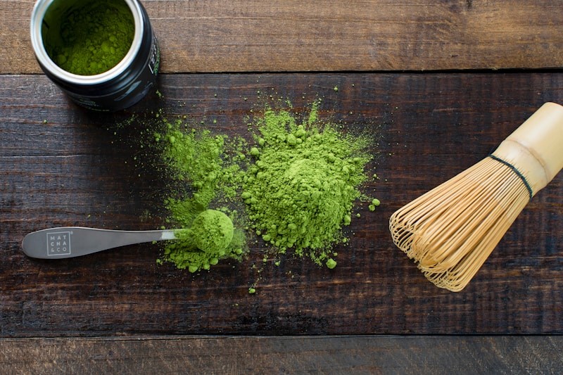 Ceremonial-grade matcha powder with chasen whisk on a wooden surface