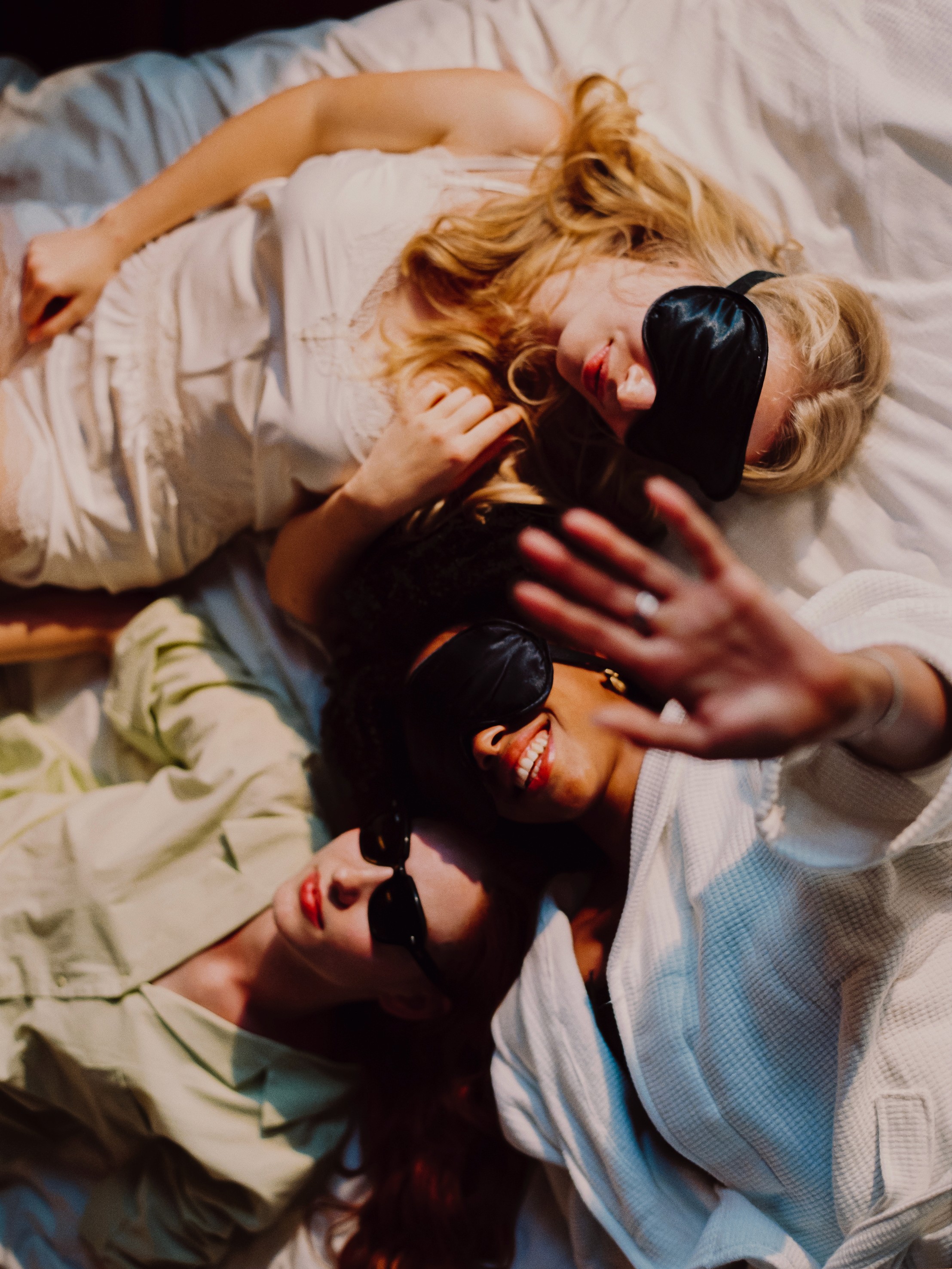 Three friends sharing a bed with sleeping masks on