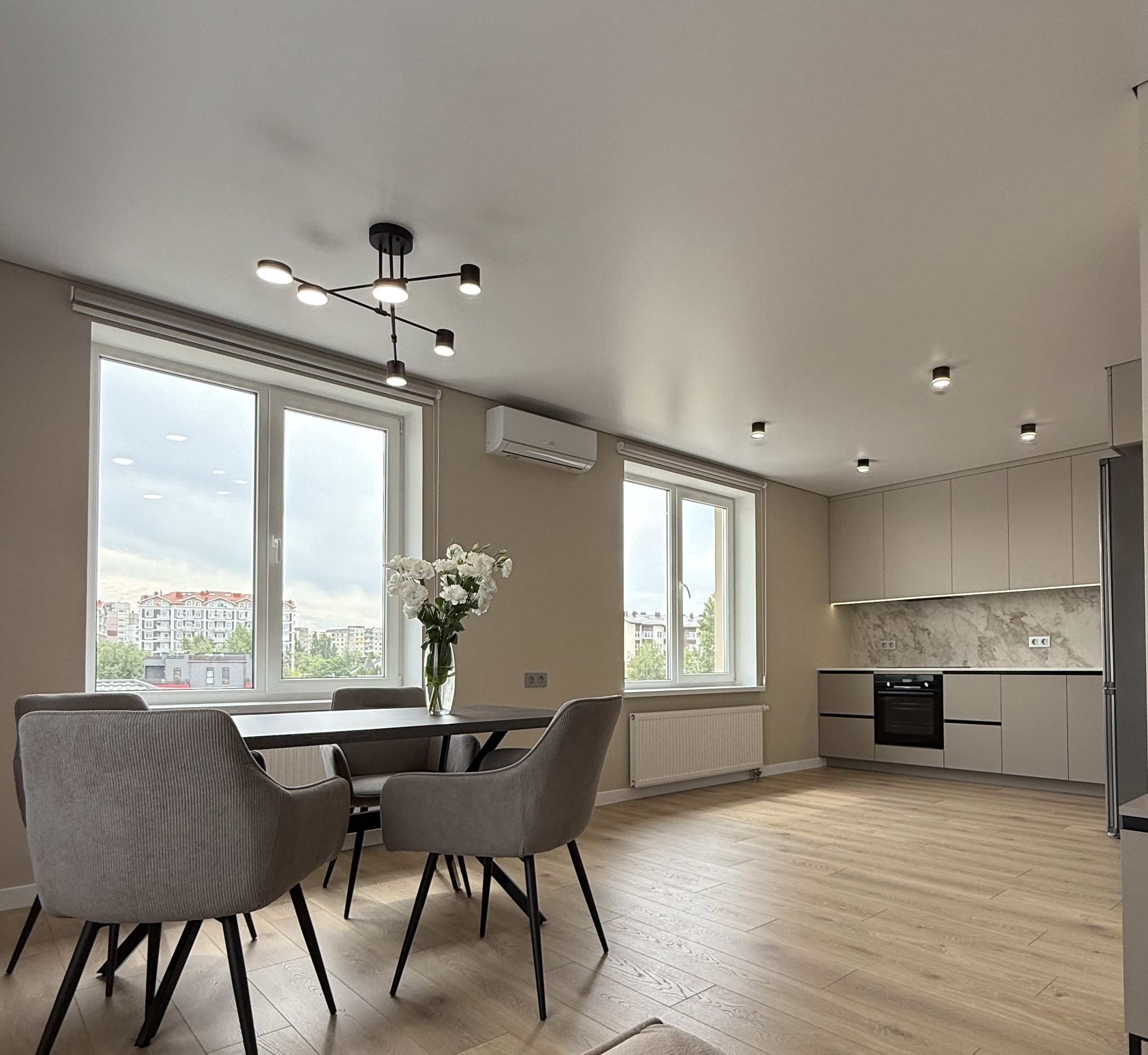 Кухня з обідньою зоною біля вікна та світлими фасадами