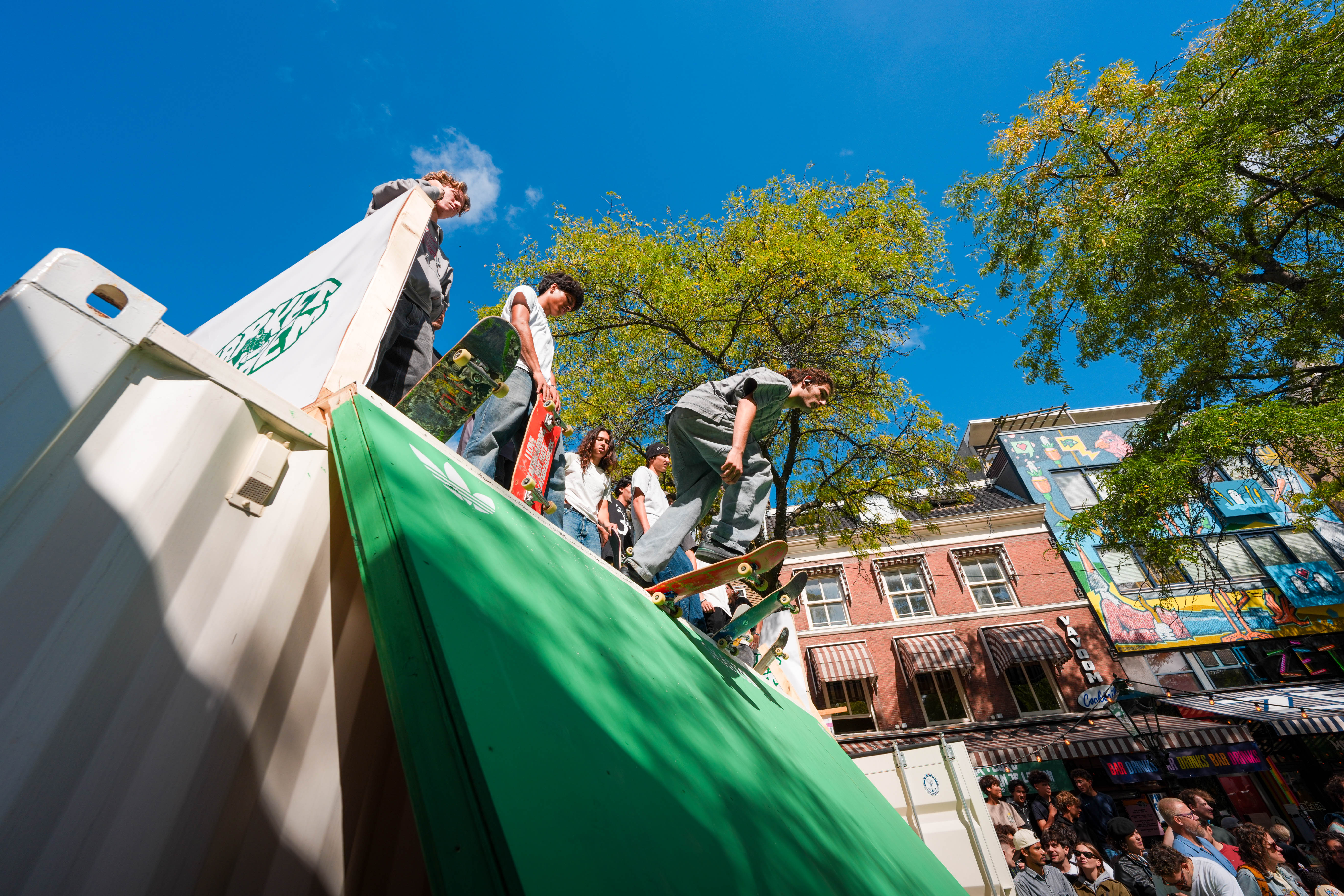 Skateboarder dropping in from the container ramp above the crowd