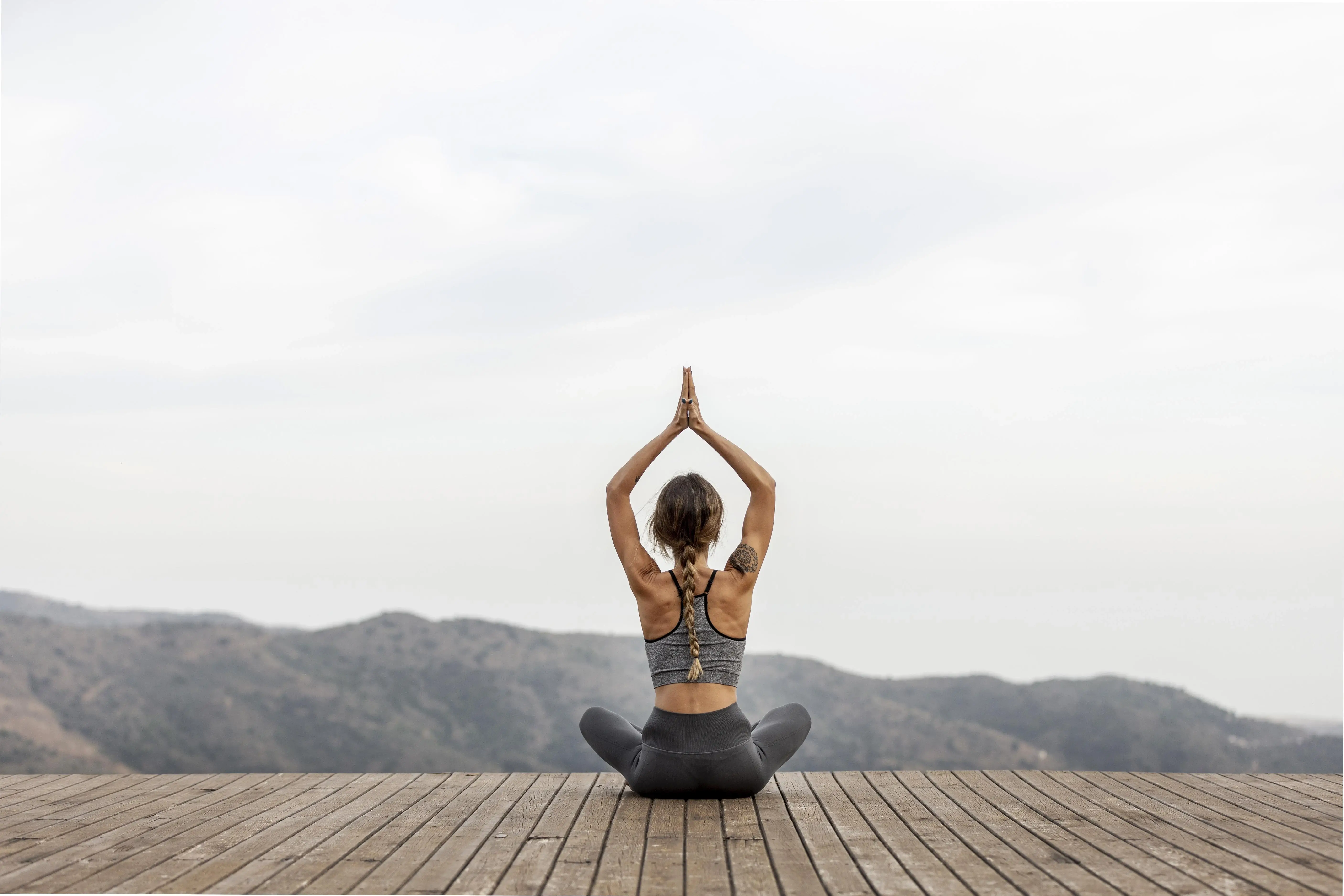 Woman practicing yoga facing the mountains at Au Revoir Wellness Resort, Palakkad, Kerala — a serene Ayurvedic retreat in the Western Ghats.