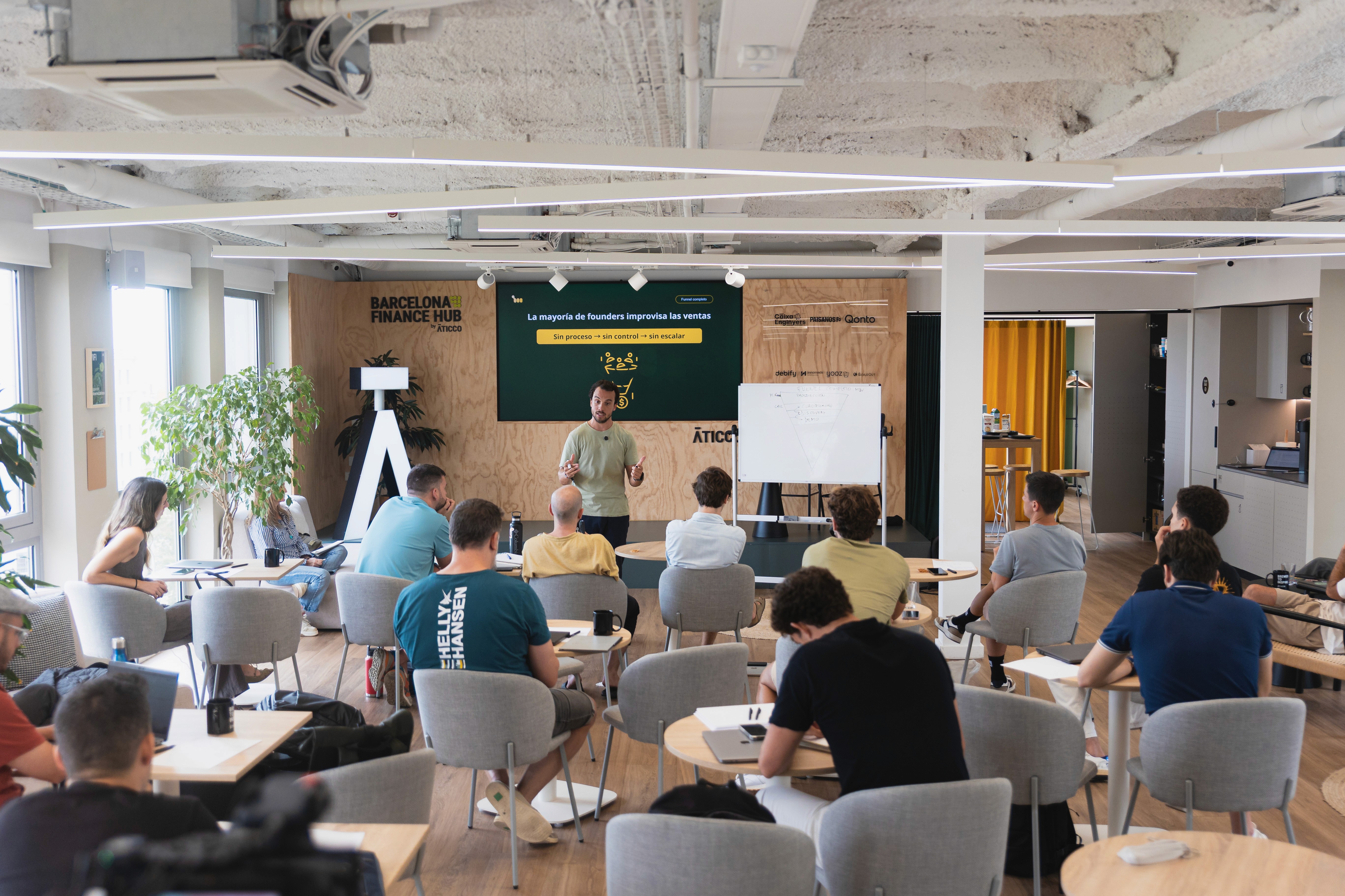 A smiling woman with her arms crossed, standing against a dark green background. She has long, dark hair.