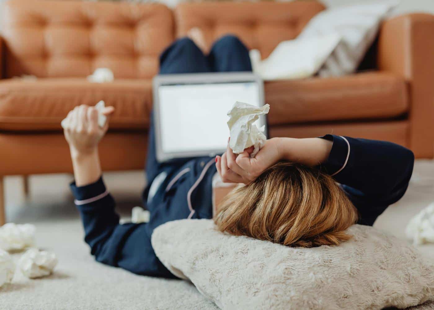 Woman using AI for a medical self diagnosis while lying on the floor and holding a tissue