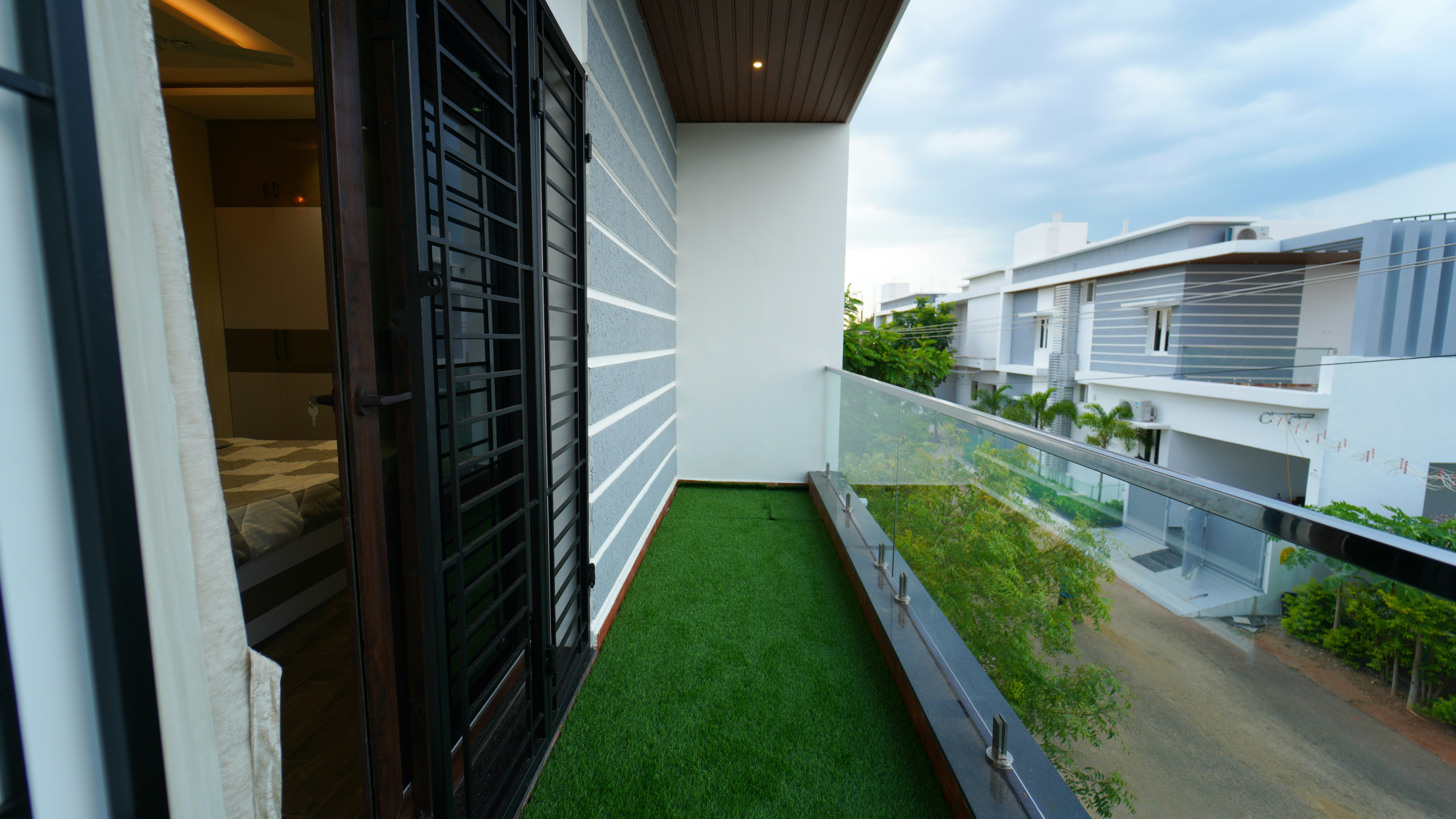 A balcony with a green lawn and a view of a building