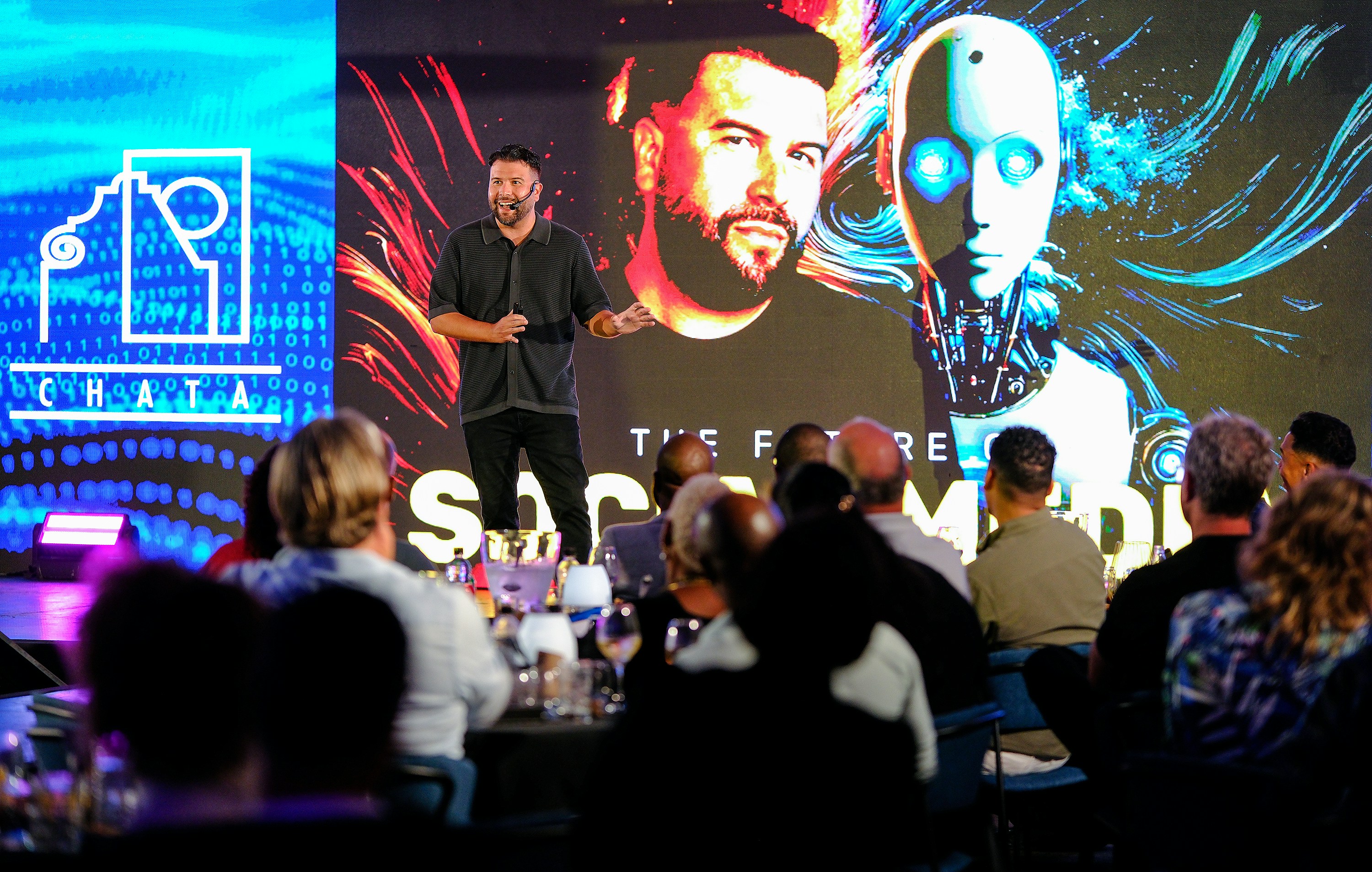 Man presents on stage with robot graphic background