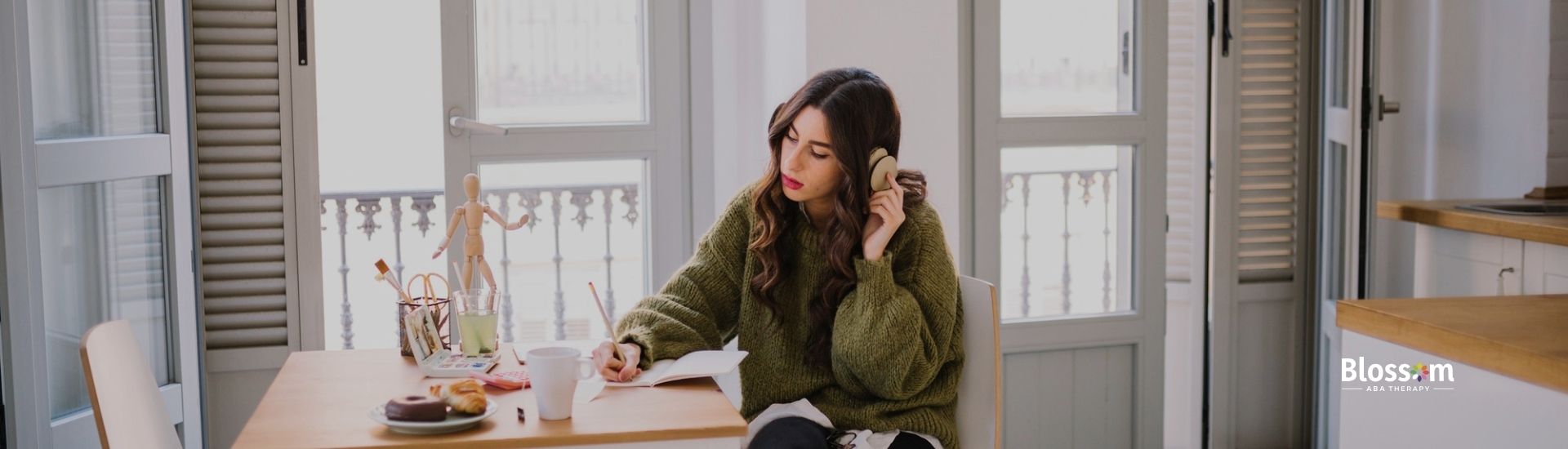 Woman sitting at a kitchen table with food, talking on the phone.