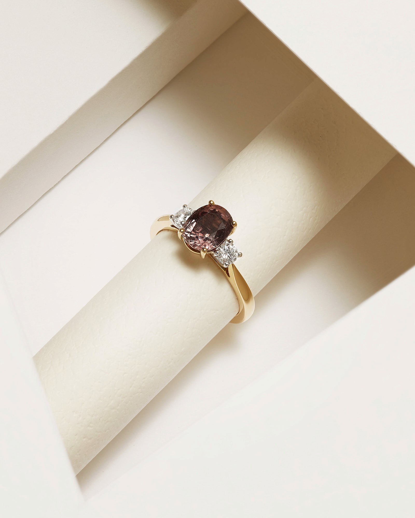 Elegant gold ring with oval purple gemstone and two sparkling diamonds.