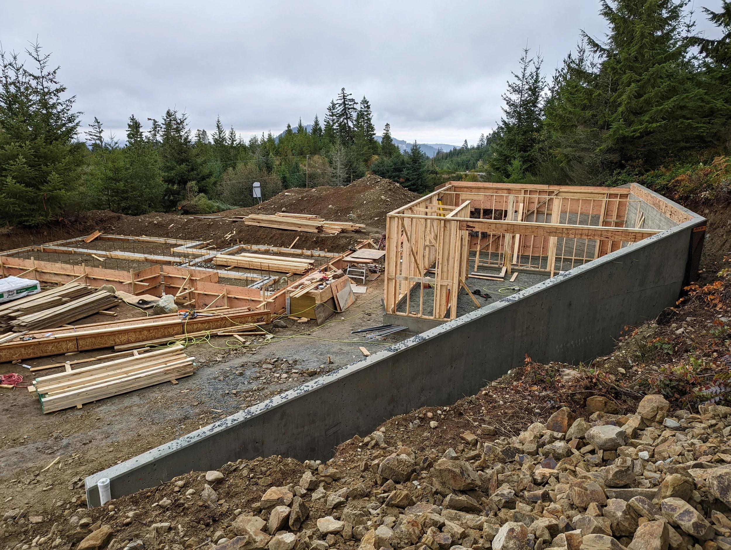 Modern two-story home with large glass windows, warmly lit interiors, and a balcony. Surrounded by trees and a manicured lawn at dusk. Cozy ambiance.