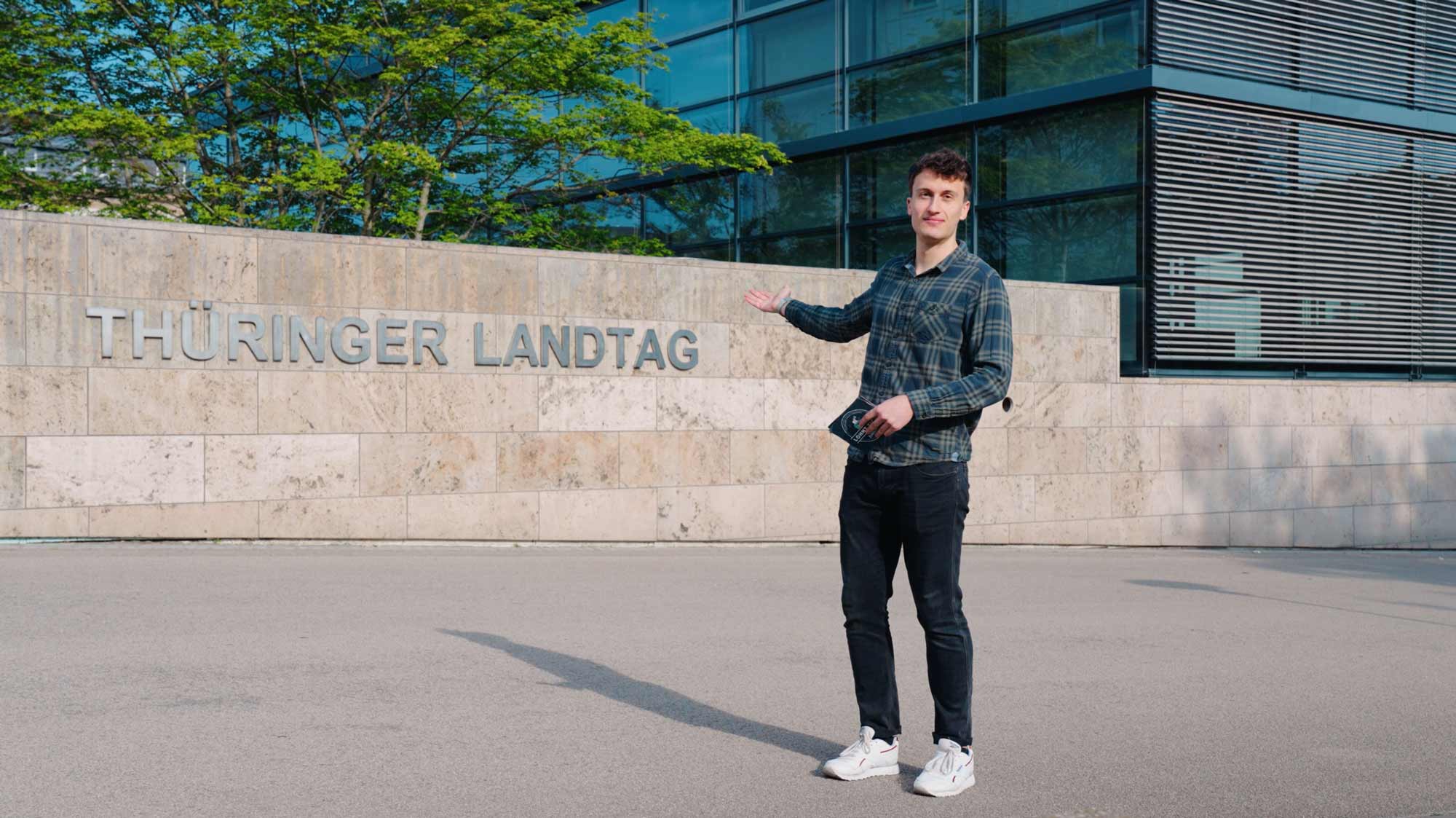 Young man in front of Thuringian parliament building, highlighting strategic film production for advertising campaigns. 