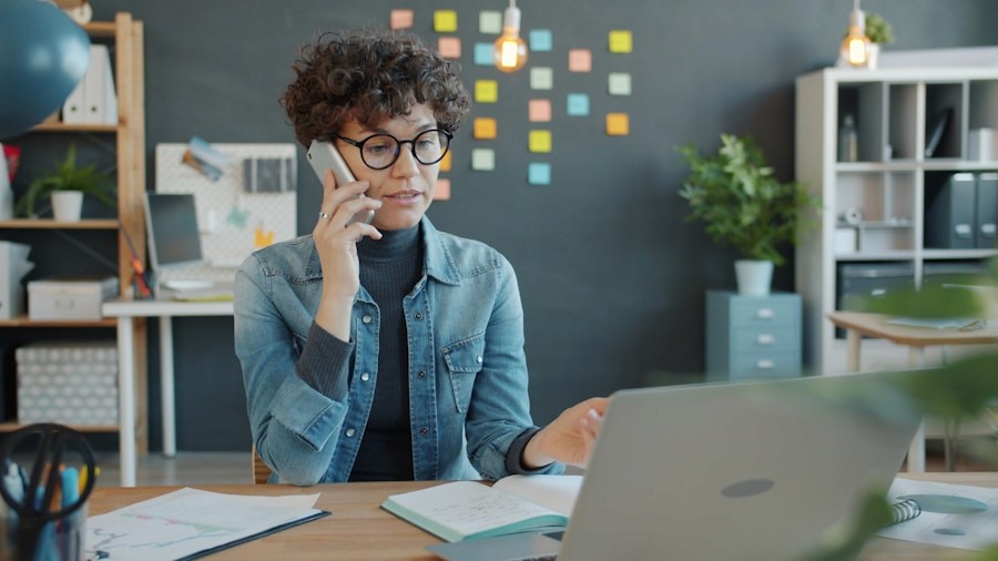 Profissional num escritório a falar ao telefone junto de um portátil