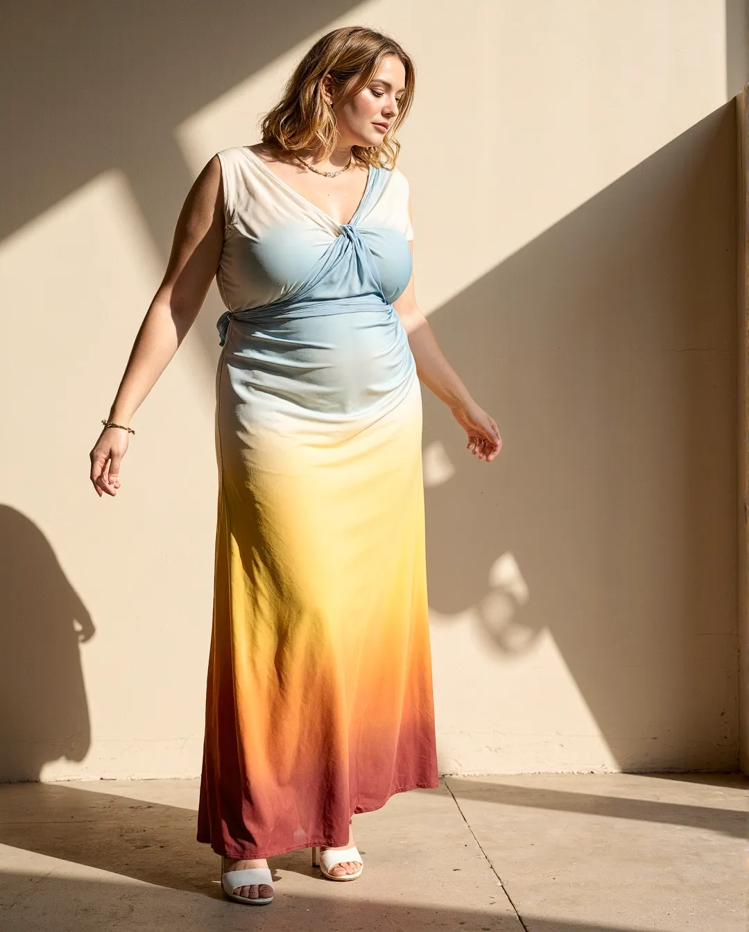 Elegant ombré maxi dress in blue, yellow and coral gradient, photographed in natural sunlight against a minimalist white wall setting