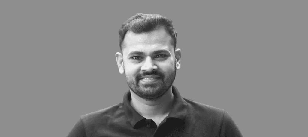 Snow-capped mountains rise above a dark, forested lake.