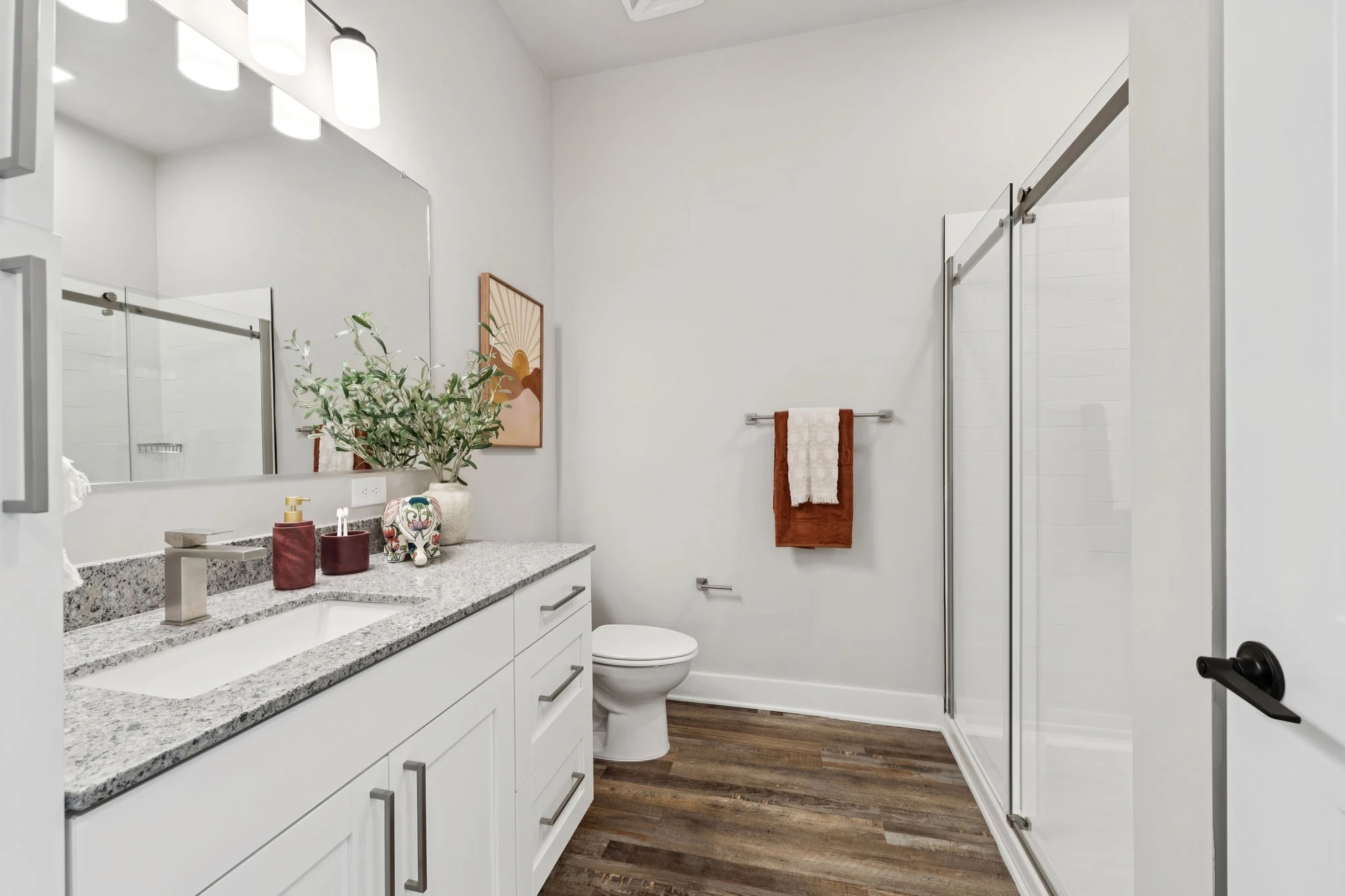 A modern bathroom featuring white cabinets and a spacious walk-in shower.