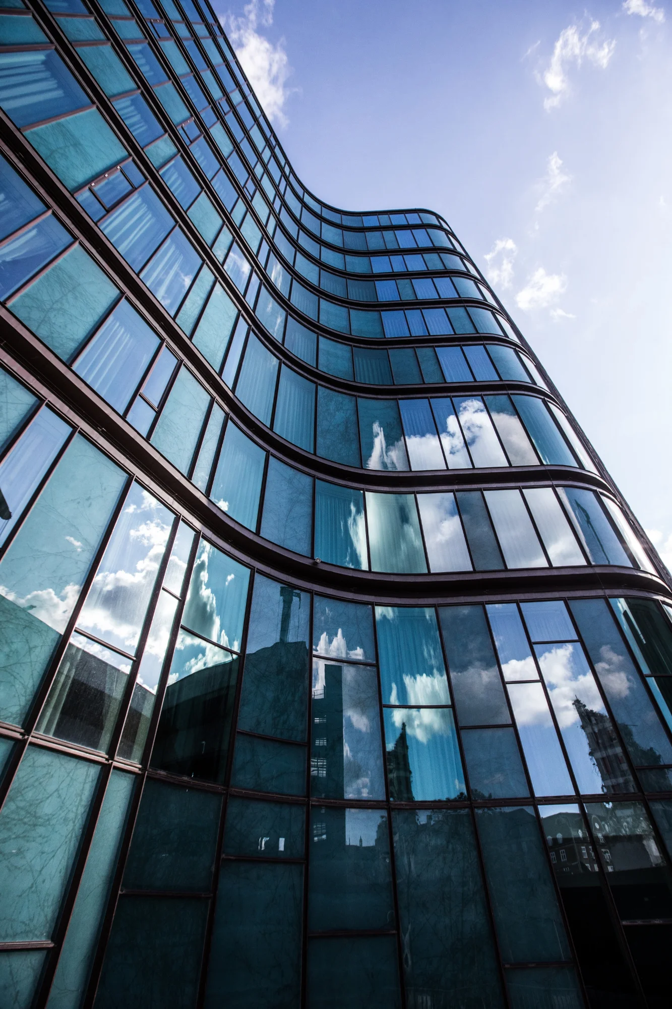 Modern apartment building with blue sky and clouds reflected in windows.