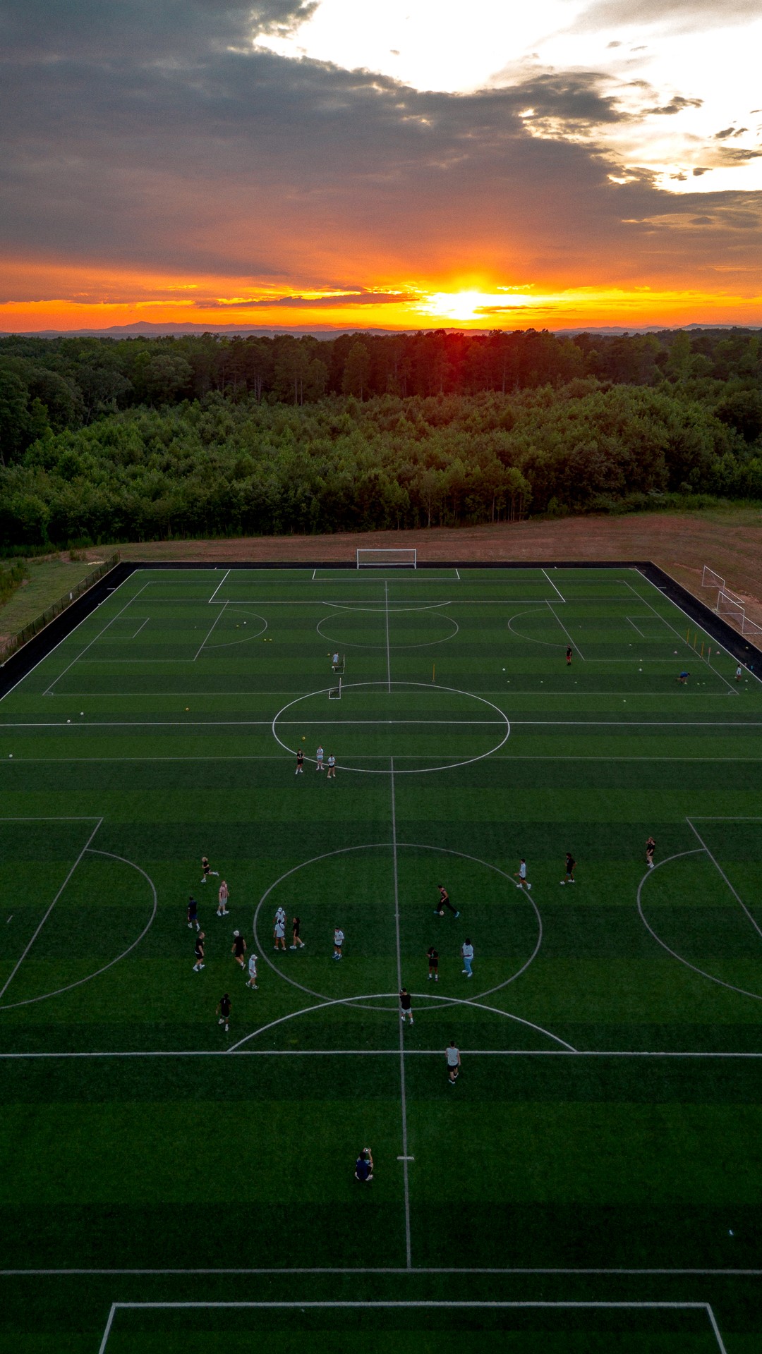 Entraînement sur terrain de foot de la Combine Academy au coucher du soleil.
