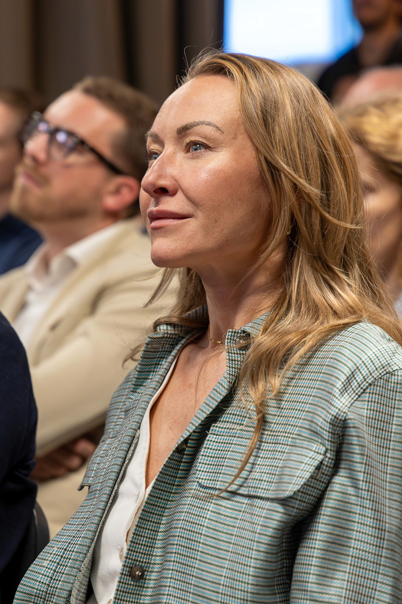 Woman listening to a keynote presentation at a blockchain event.