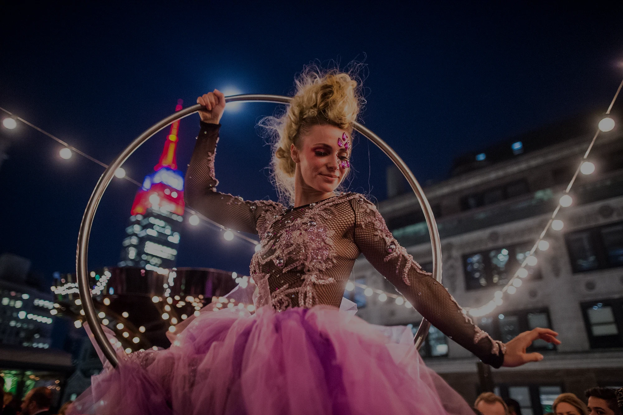 Aerial hoop performer at a holiday party with the Empire State Building behind