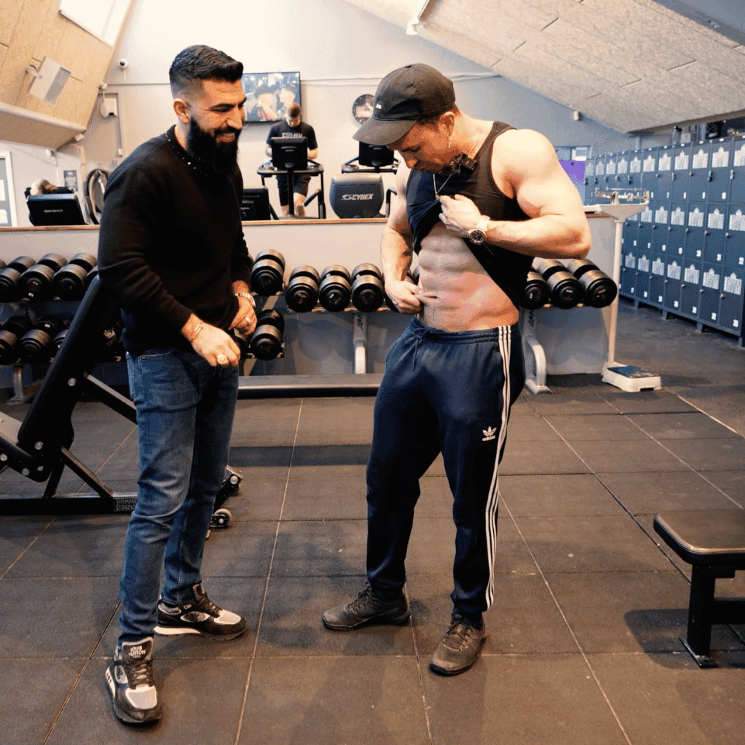 Online coach Ashkan gennemgår klient Gustav Salinas udvikling og træningsplan i fitnesscenter.