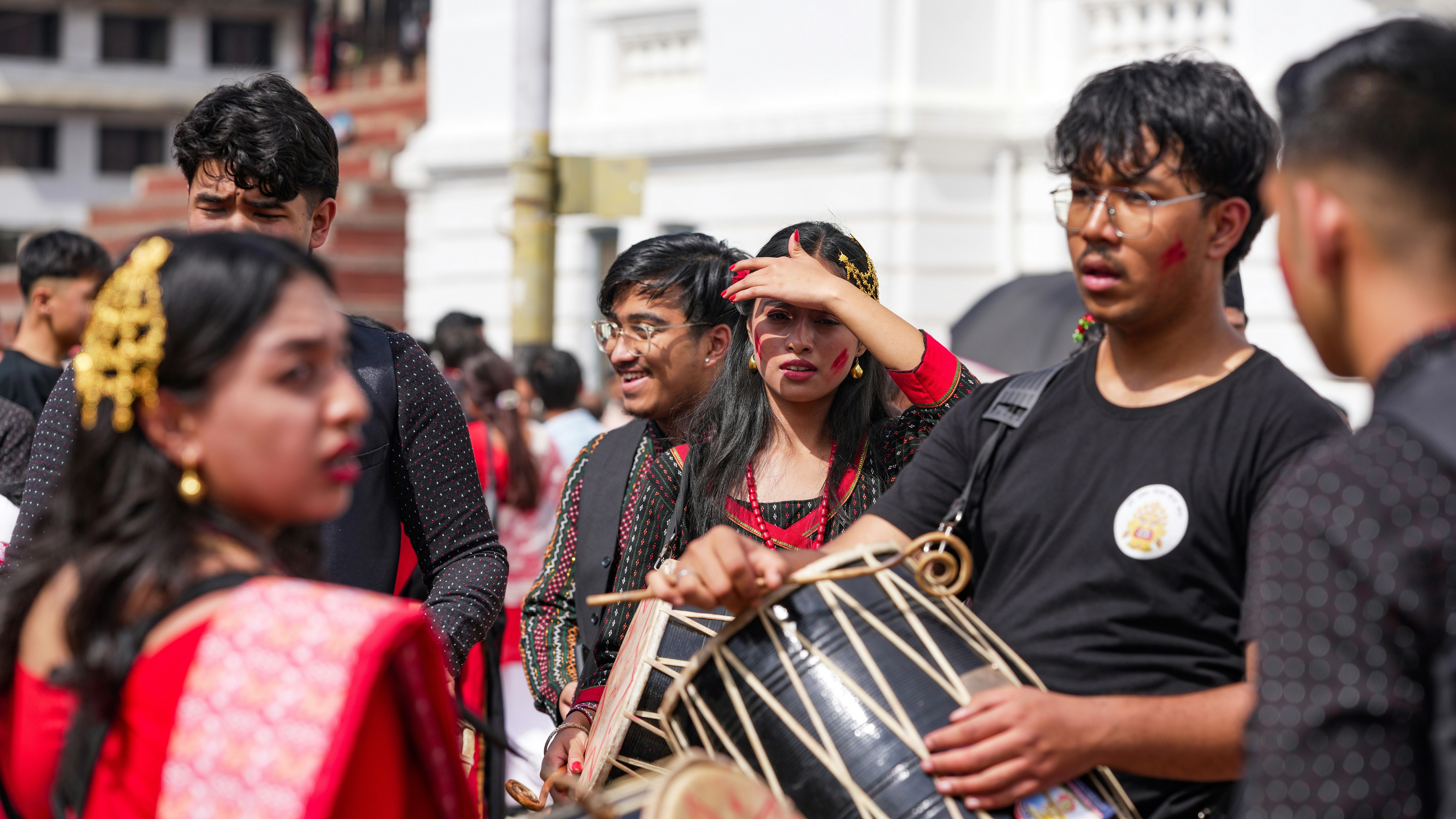 People in traditional clothing playing a drum.