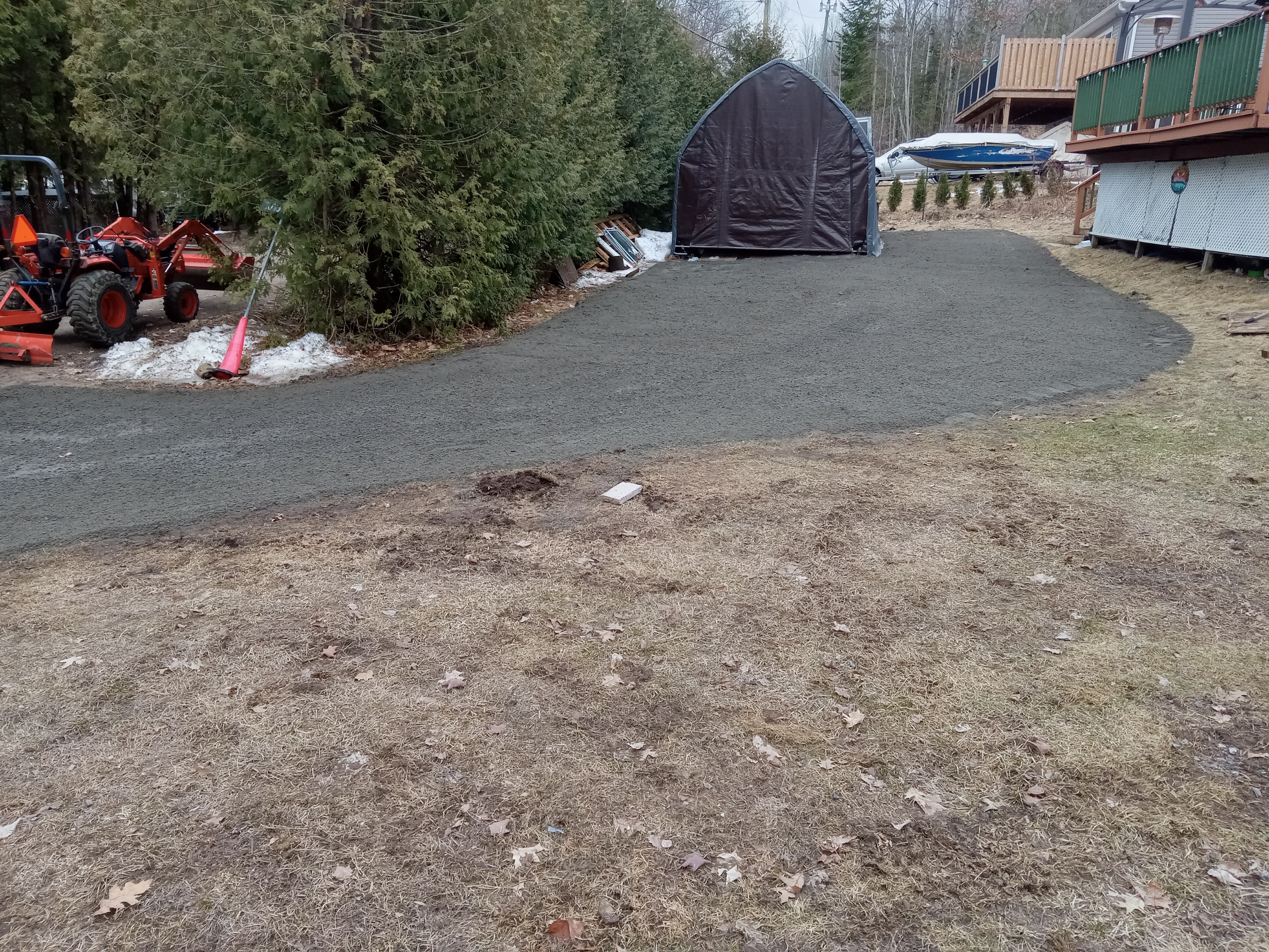 Completed gravel driveway and parking area beside a cottage storage shelter.