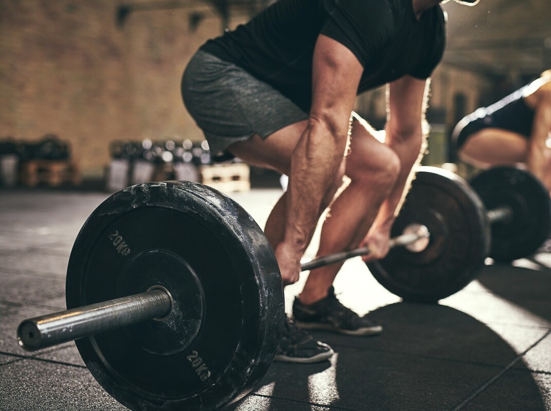 man doing a deadlift with heavy weights as part of his routine of workouts to lose weight at gym