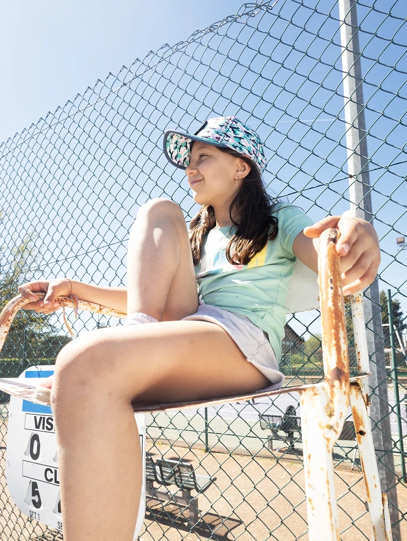 Casquette colorée The Prompt Factory portée en situation sur un court de tennis