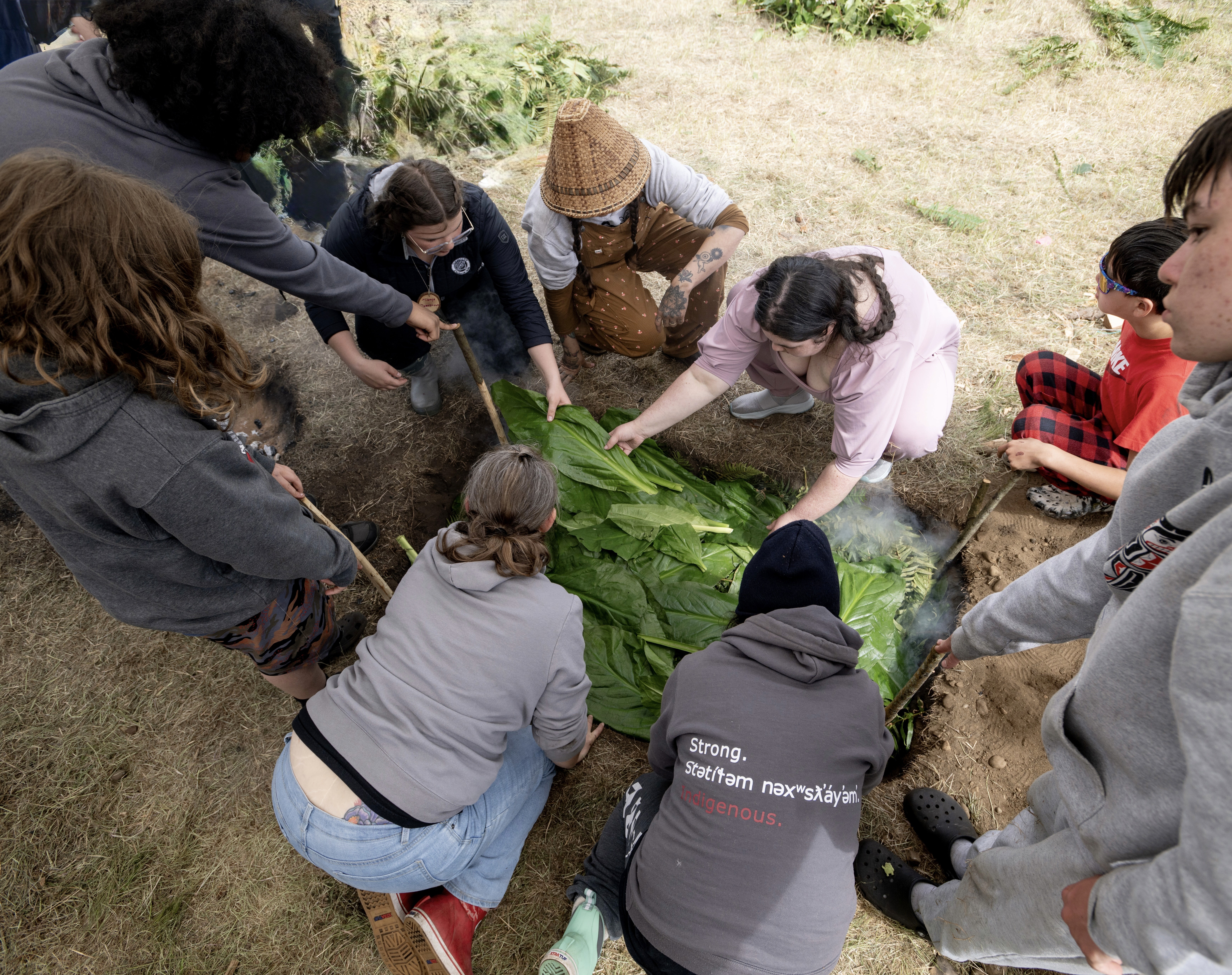 Wrapped camas is loaded into the pit bake oven. Photo by: Hannah Letinich