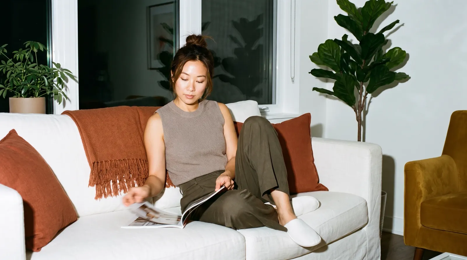 A woman reading a magazine on a white sofa