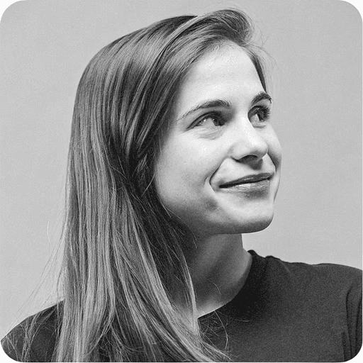 Portrait of a young man with short hair, wearing a dark t-shirt, against a plain background.