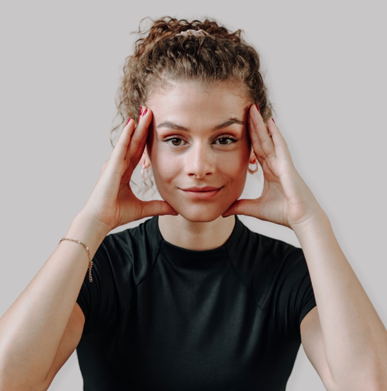Smiling blonde woman with freckles in a white shirt, arms crossed, minimalist studio portrait.