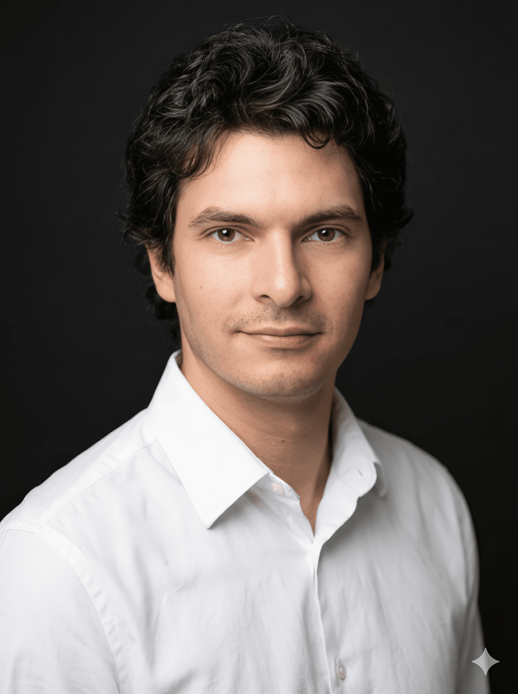 Close-up portrait of a person wearing a gray insulated hooded jacket with the hood up, showing their face framed by the hood against a light background.