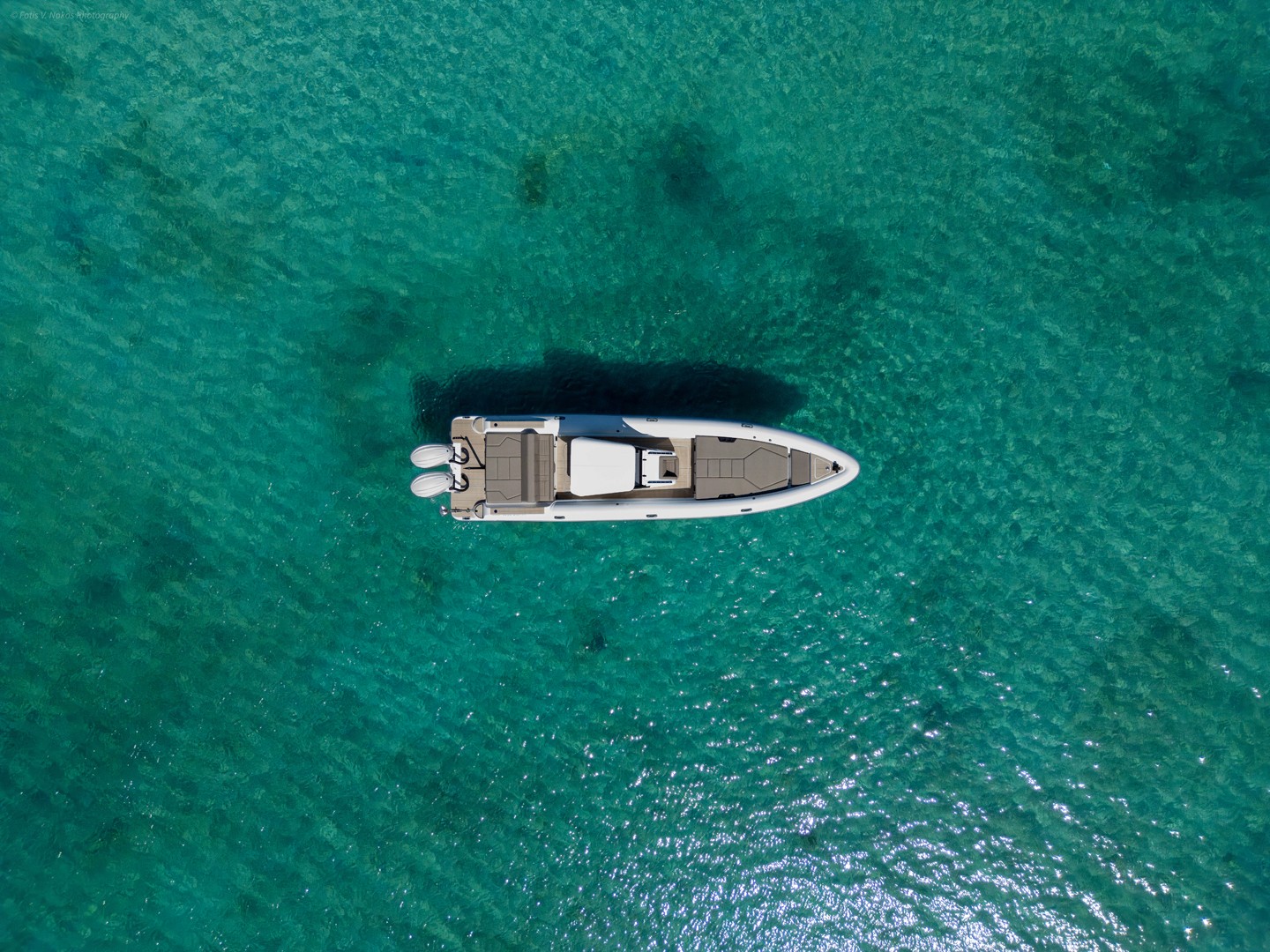 White Rock 36 motor yacht with twin outboard engines anchored in crystal-clear turquoise waters of the Cyclades.