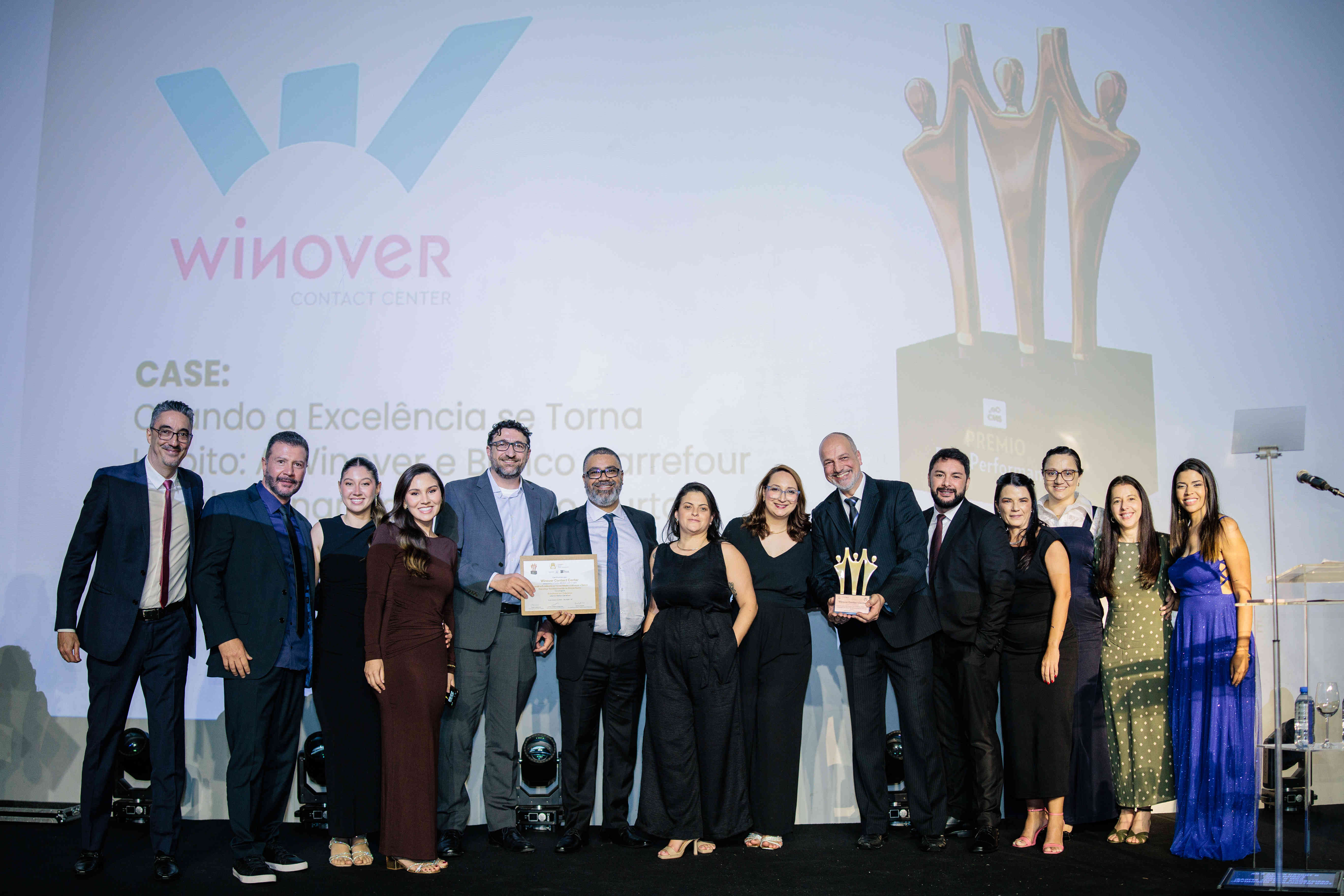 Executivos da Winover Contact Center posando com troféu bronze e certificado no palco do Prêmio Best Performance 2025