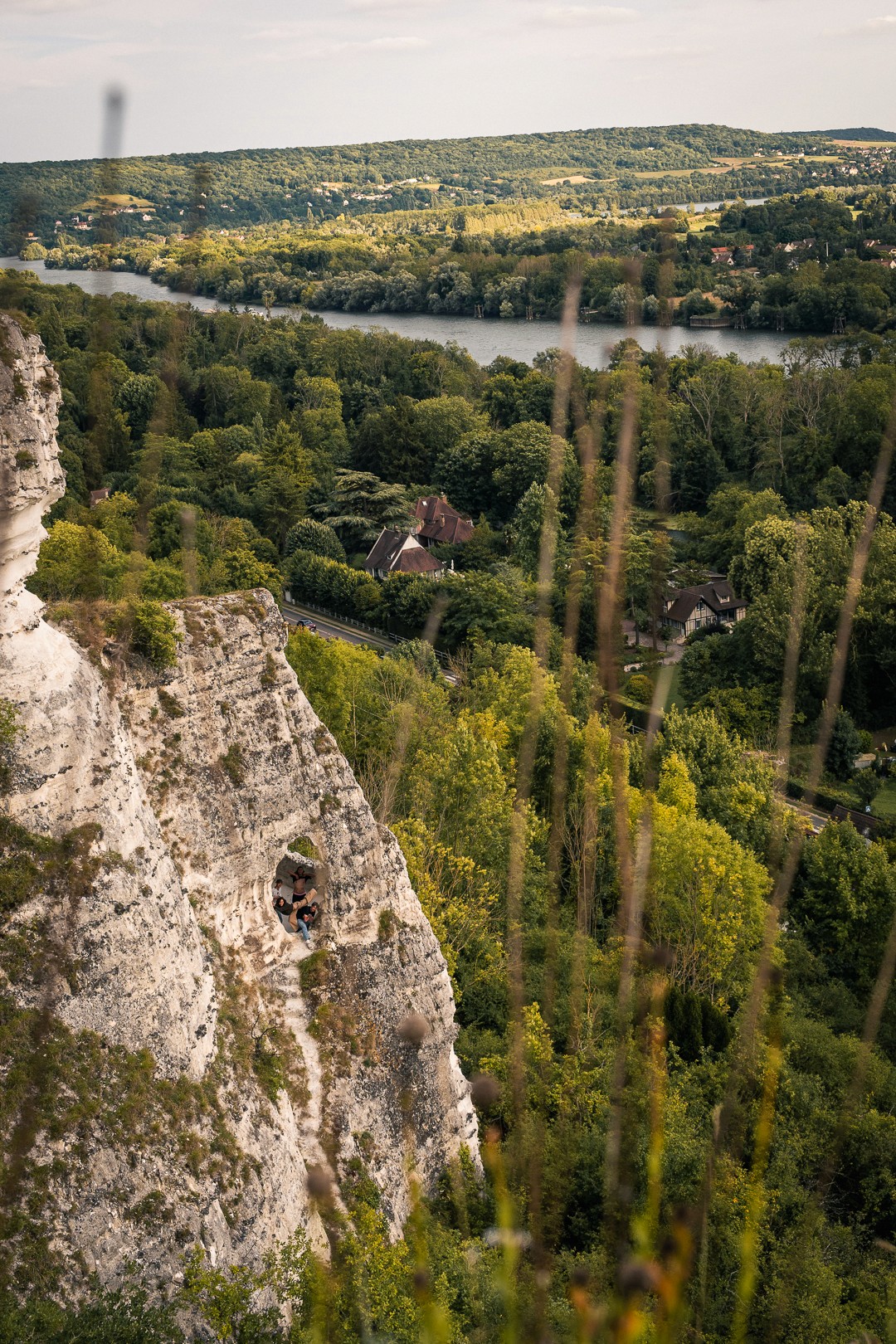 Falaise percée d’un trou circulaire avec équipe visible à l’intérieur.