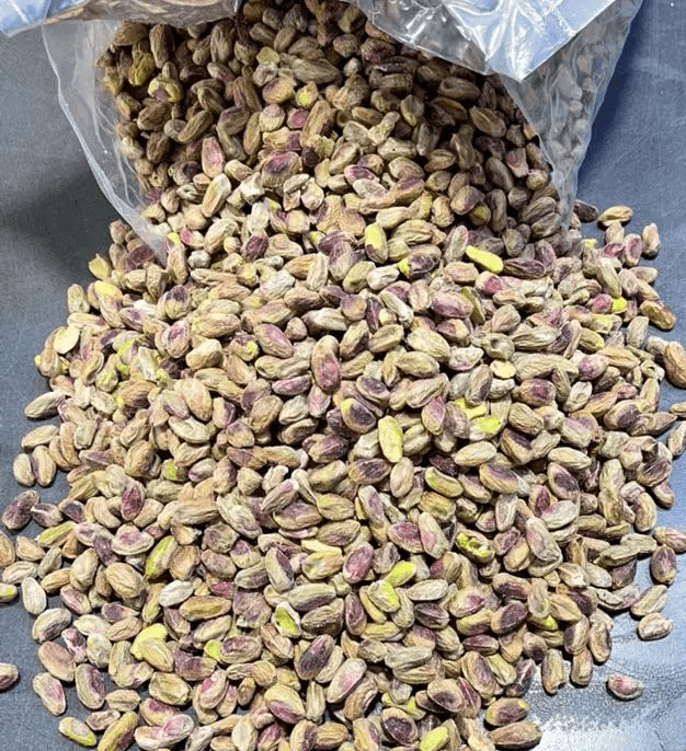 Skin-on pistachio kernels shown loose from an open bulk bag.