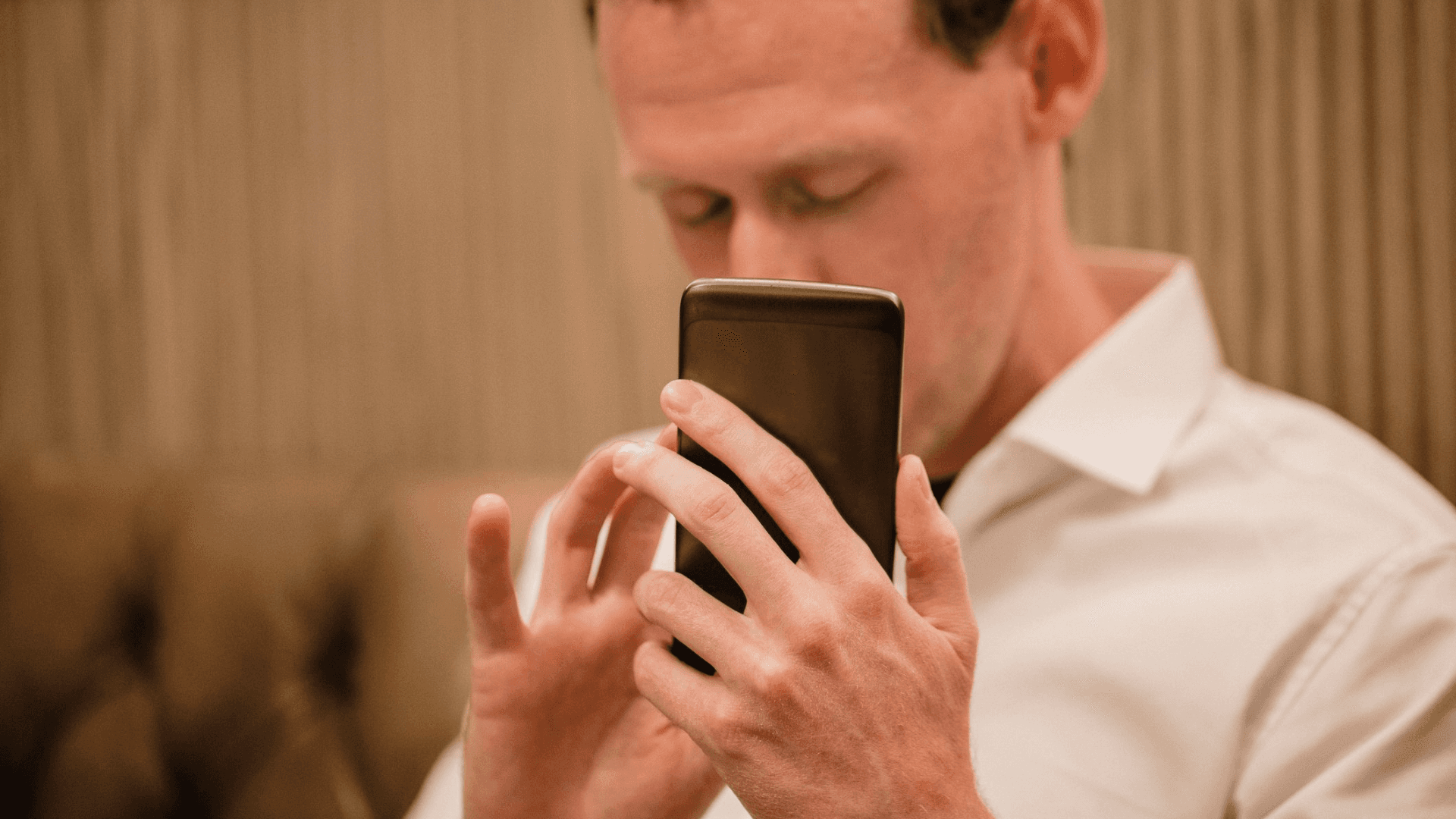 A person with their eyes closed holding a phone close to their face to use