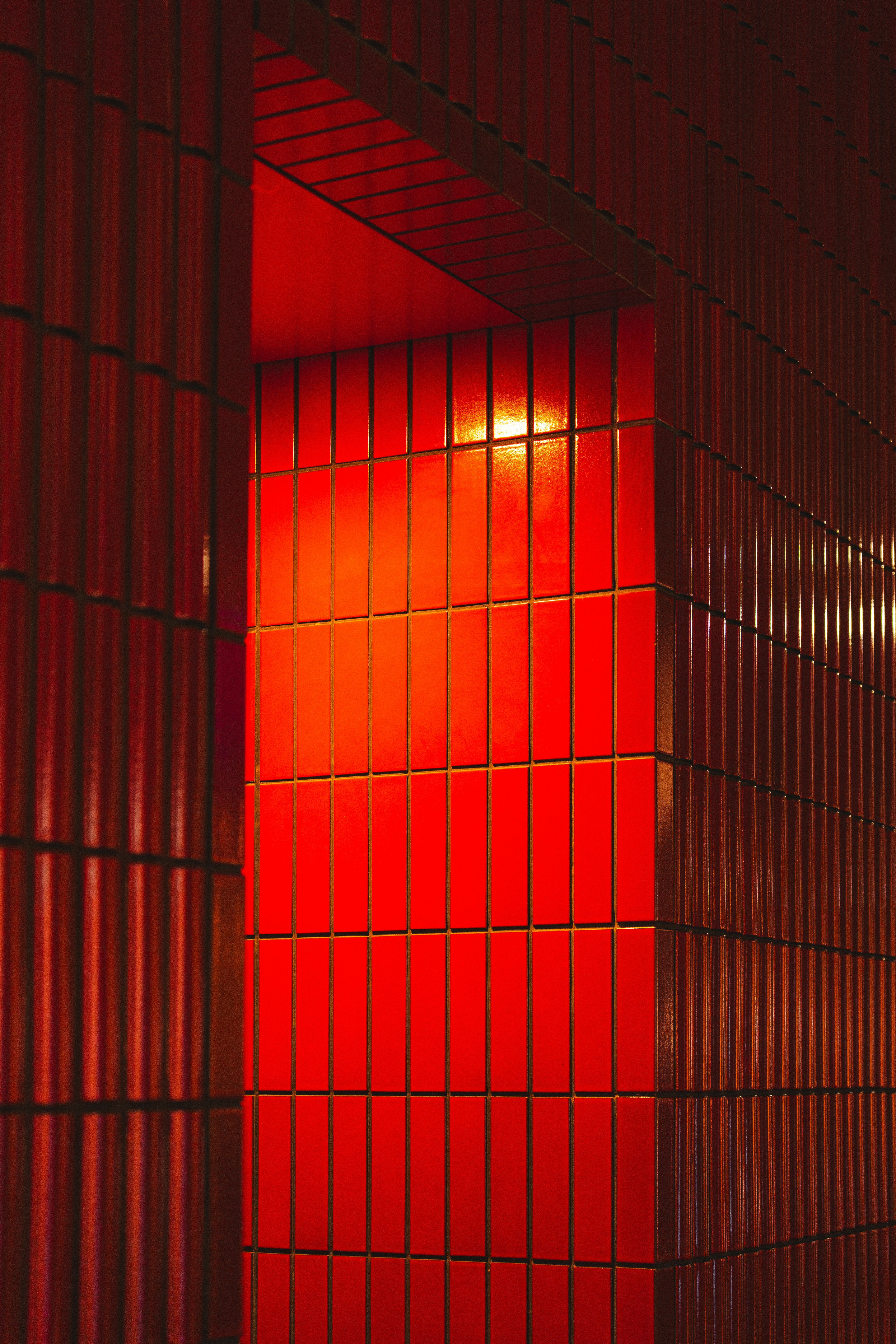 Vibrant red tiled wall illuminated by warm light.