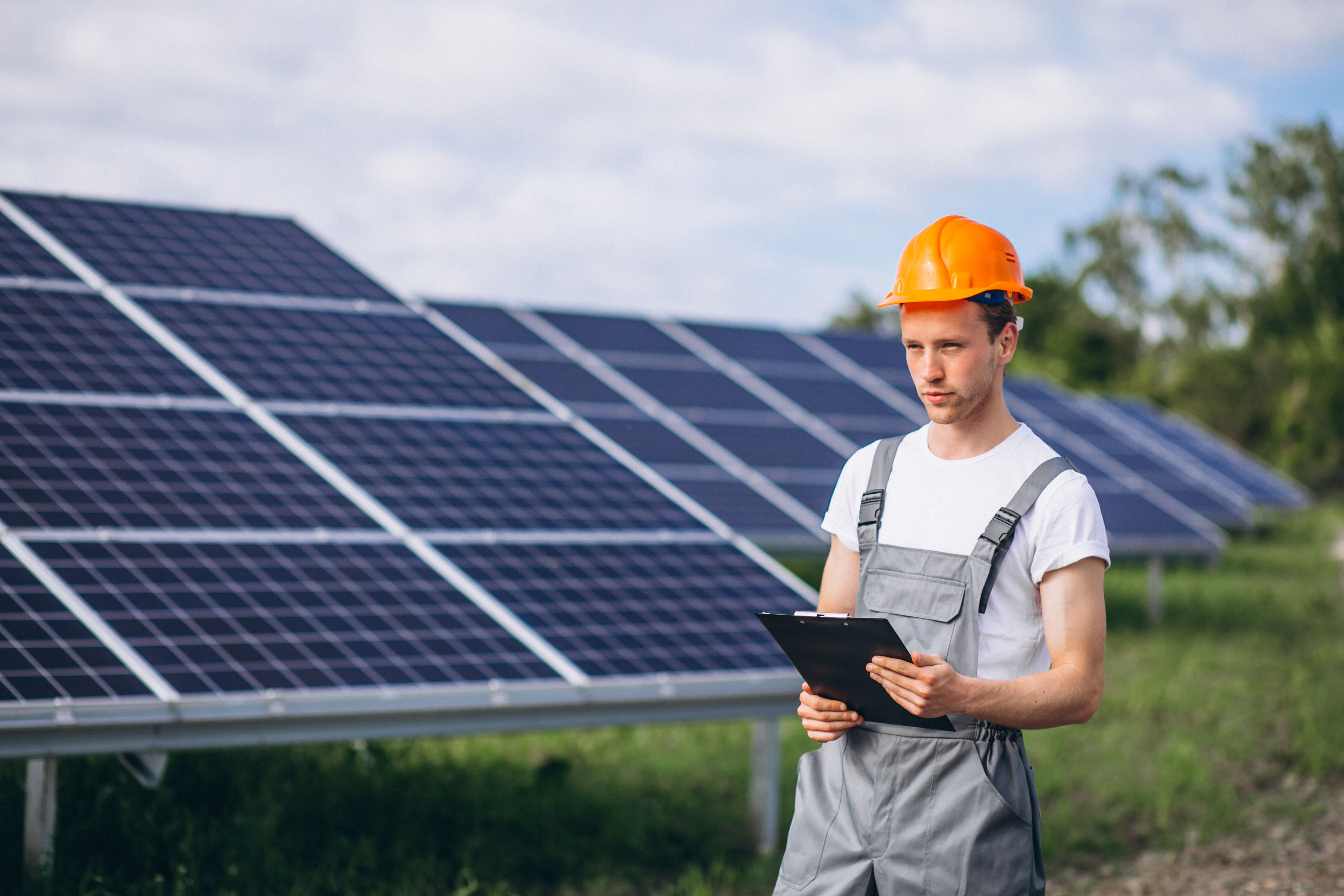 Man in hard hat with clipboard near solar panels