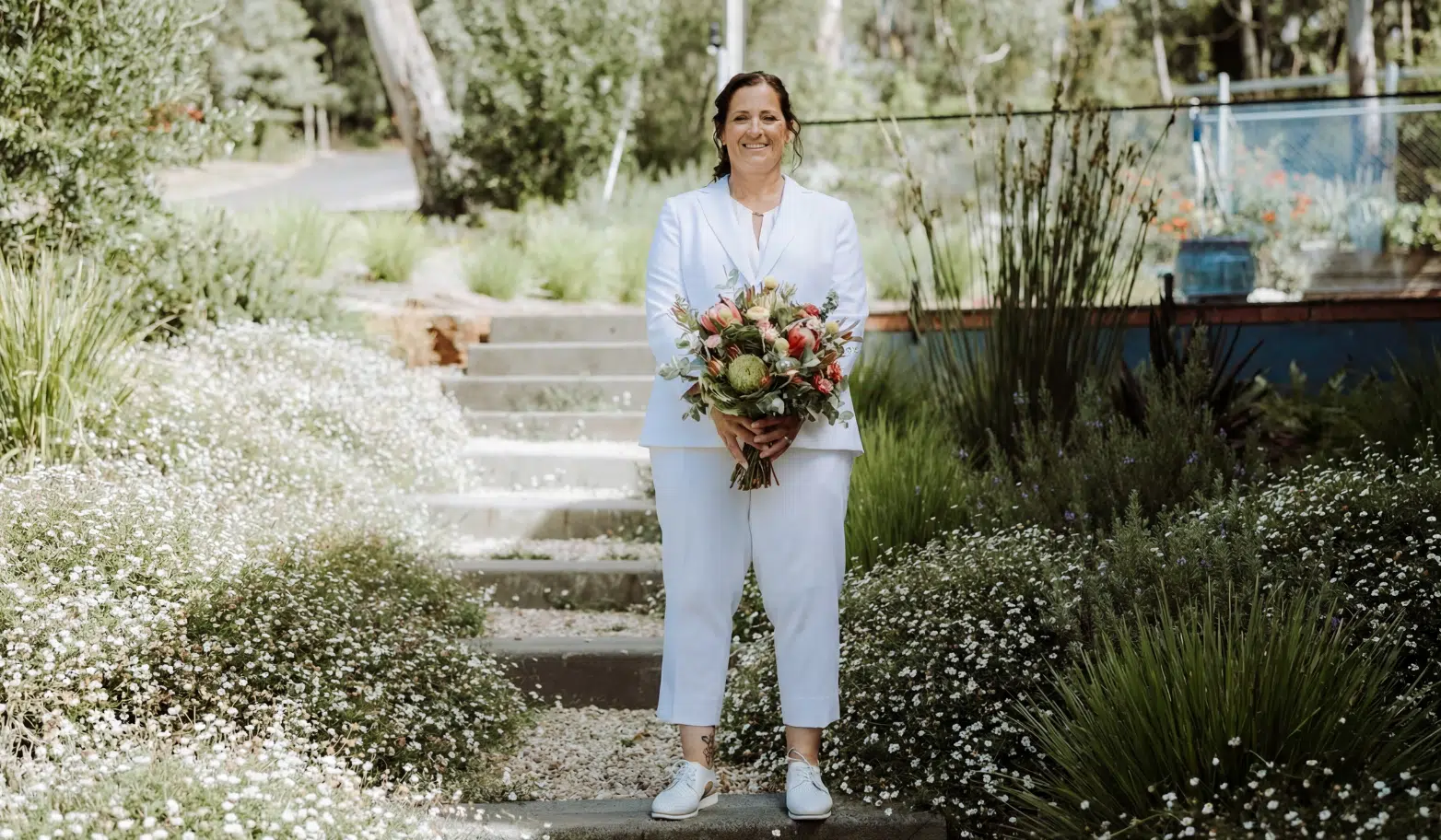 Women’s wedding suit styles in New Zealand with bride in tailored rust suit and modern outdoor ceremony look