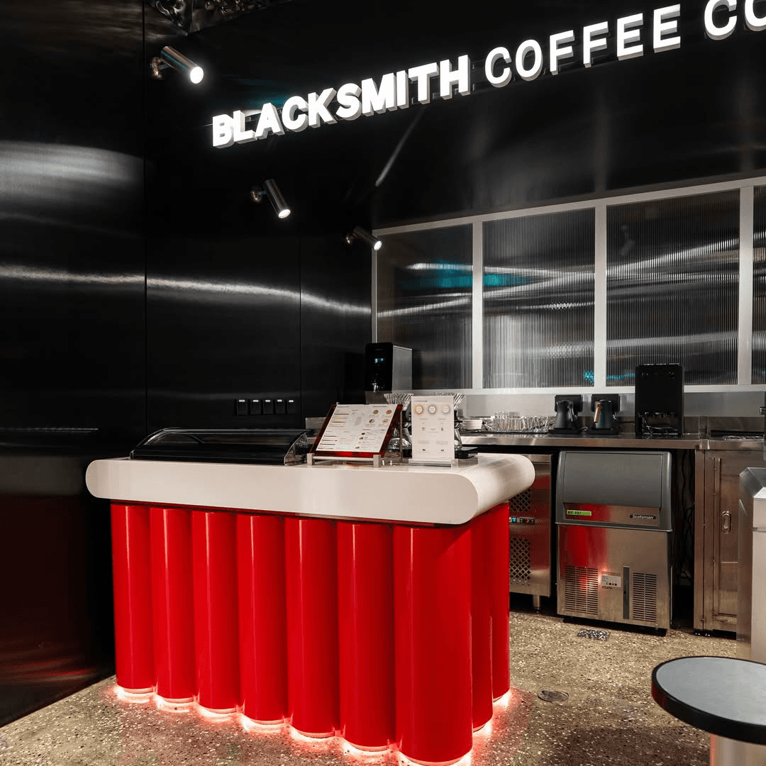 Sleek, modern cafe counter with a red cylindrical base and metallic accents at Blacksmith Coffee Company.