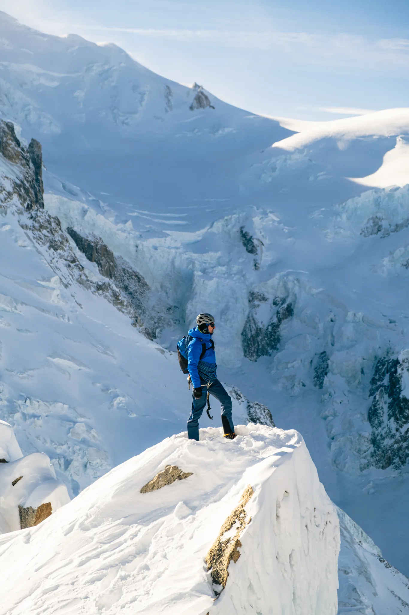 Alpiniste au sommet enneigé observant le panorama du massif du Mont-Blanc, équipé Millet.