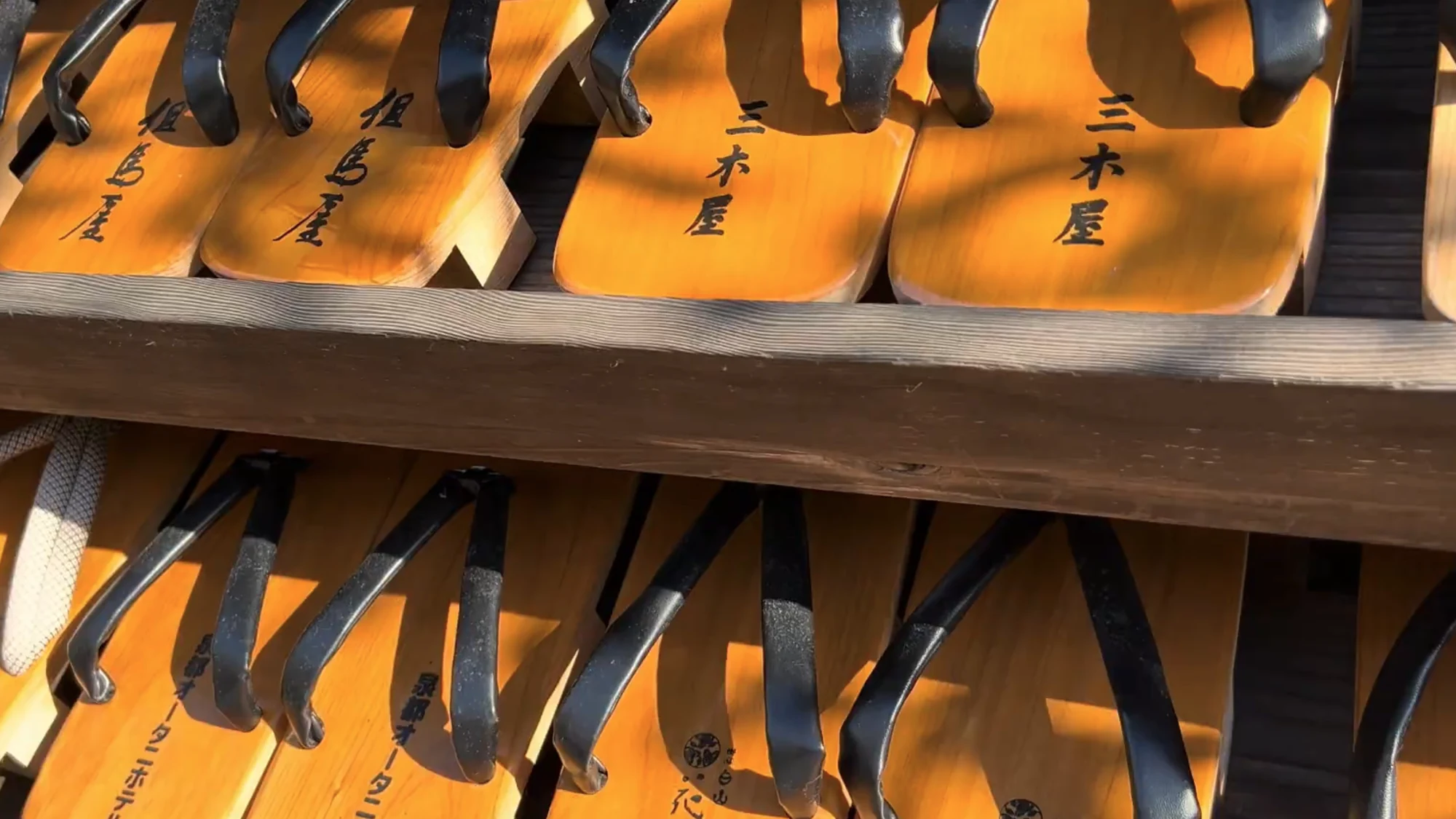 Wooden geta stamped with an inn's name stacked on a rack in Kinosaki.
