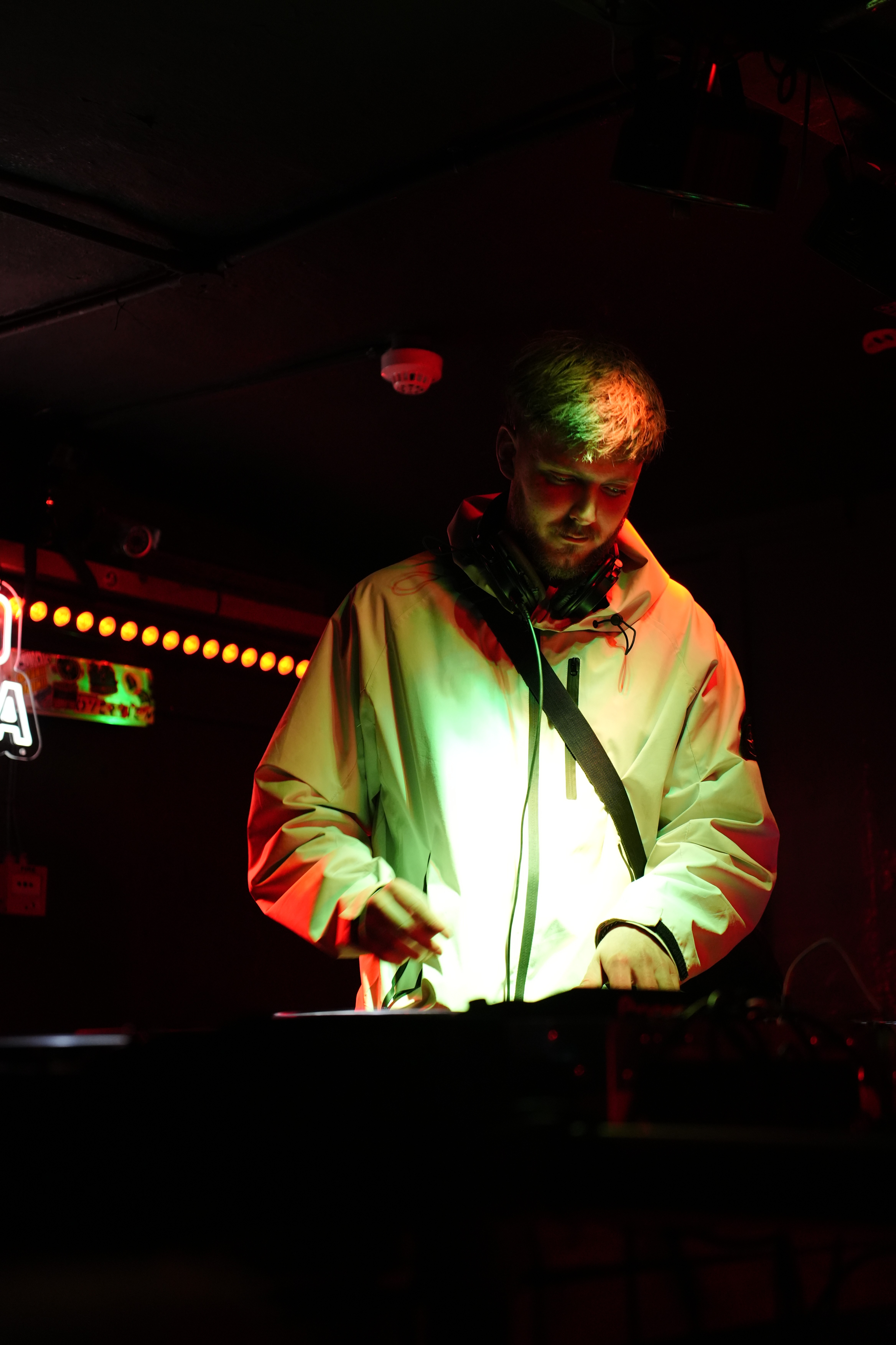 A person holding a camera is silhouetted against vivid orange stage lights. The scene conveys focus and creativity with a dramatic, moody atmosphere.