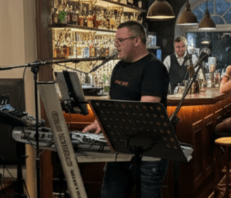 Člen Duo Forte hrá na klávesoch v bare počas večerného programu