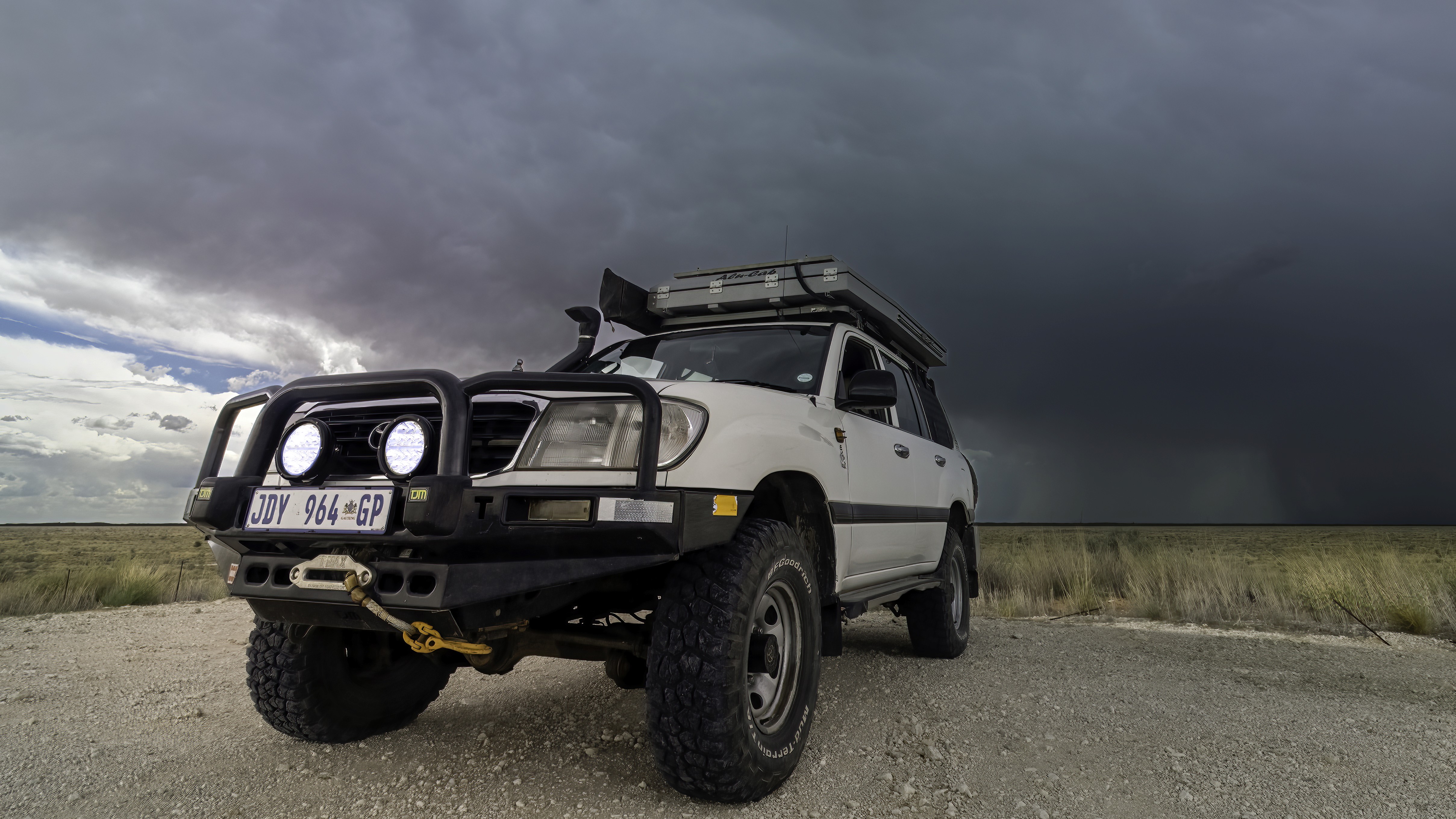 A Toyota Land Cruiser fitted for expedition travel, under a storm sky.