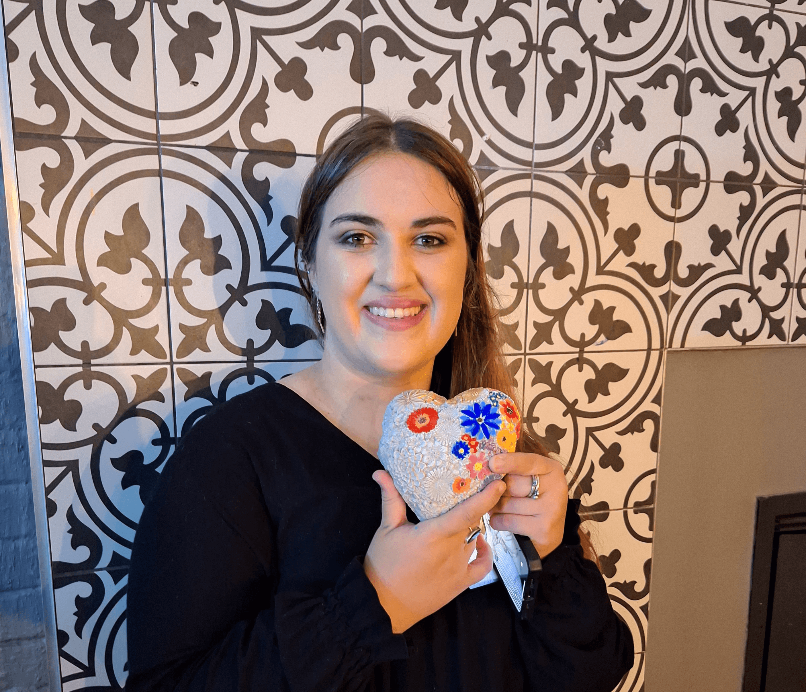 A woman smiling and showing her artwork
